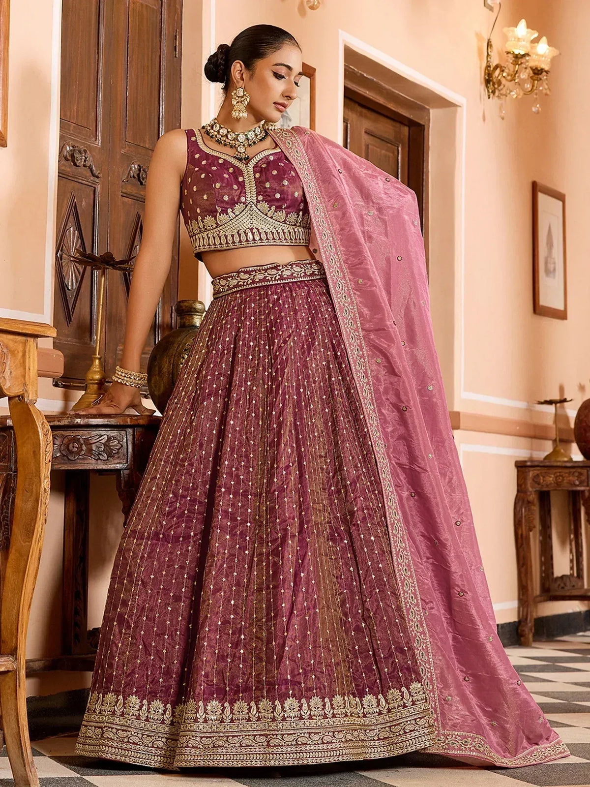 Elegant maroon lehenga choli with gold embroidery, paired with pink dupatta, perfect for Indian ethnic wear occasions.