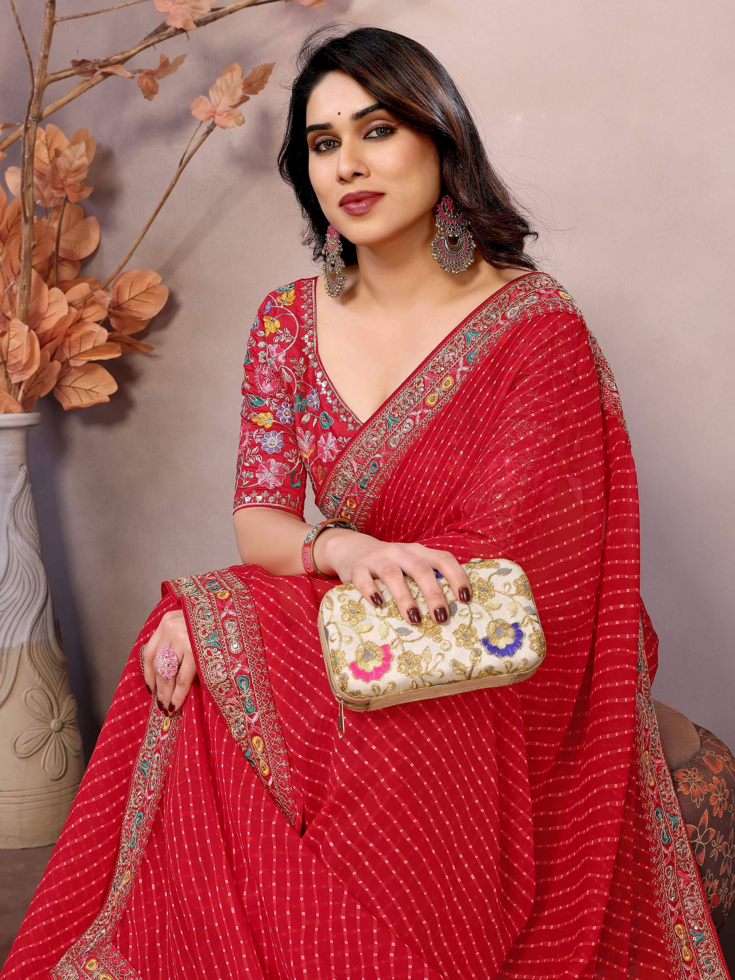 Red embroidered saree with floral designs, paired with matching blouse and clutch for ethnic wear