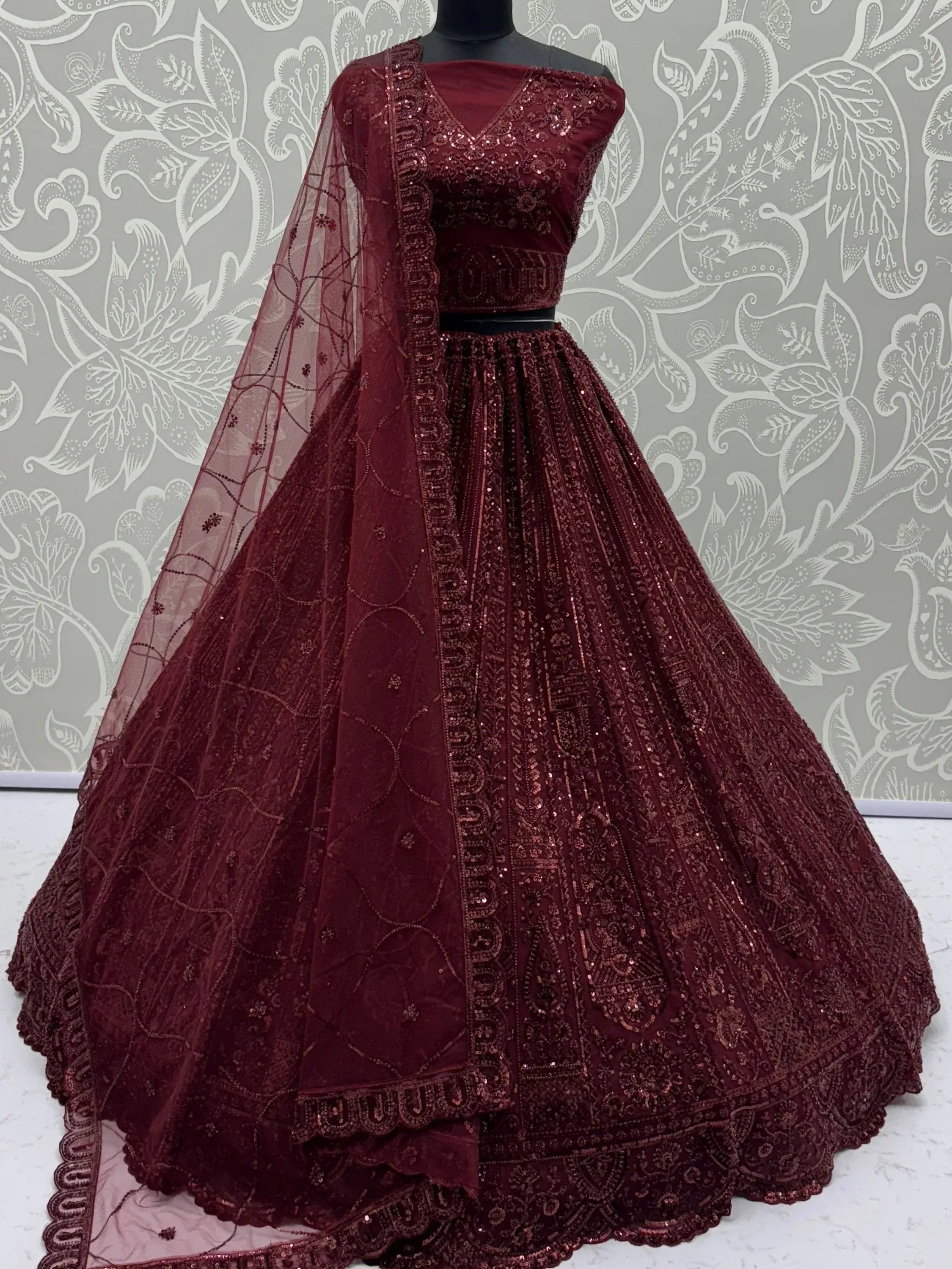 Burgundy designer lehenga choli with heavy sequin embroidery and net dupatta, ideal for weddings and festive occasions.