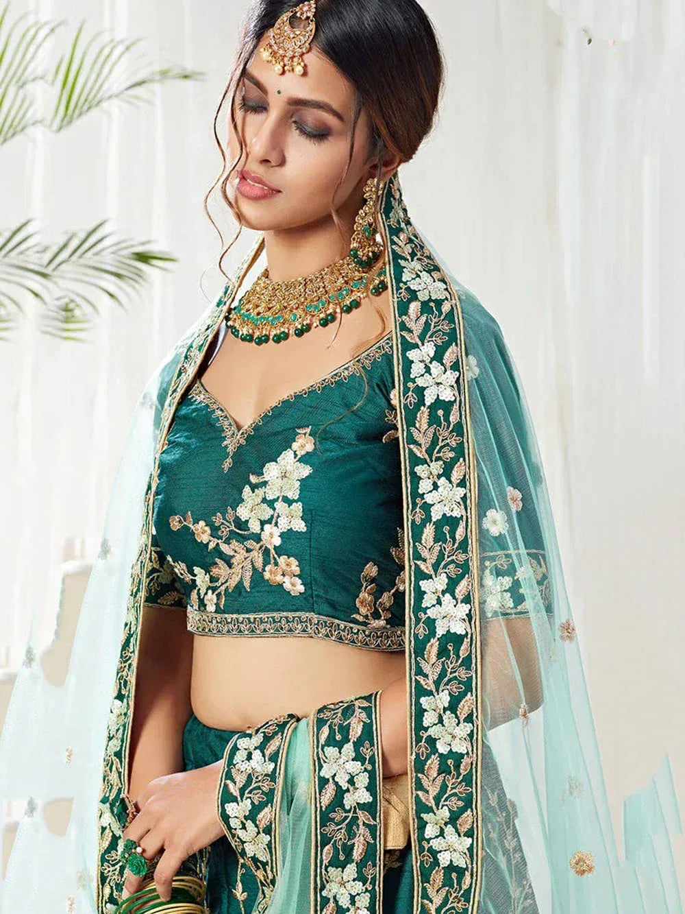 Emerald green embroidered lehenga choli with floral motifs and sheer dupatta, perfect for Indian weddings and festive occasions.