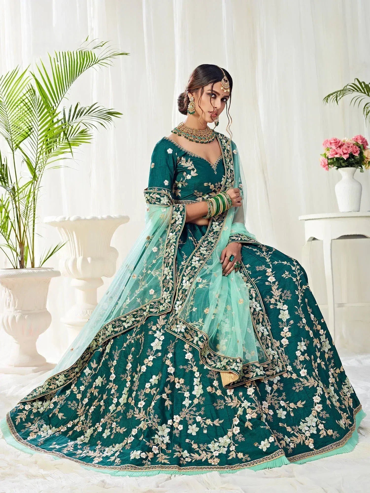 Emerald green designer lehenga choli with floral embroidery and sheer dupatta, perfect for weddings and festive occasions.