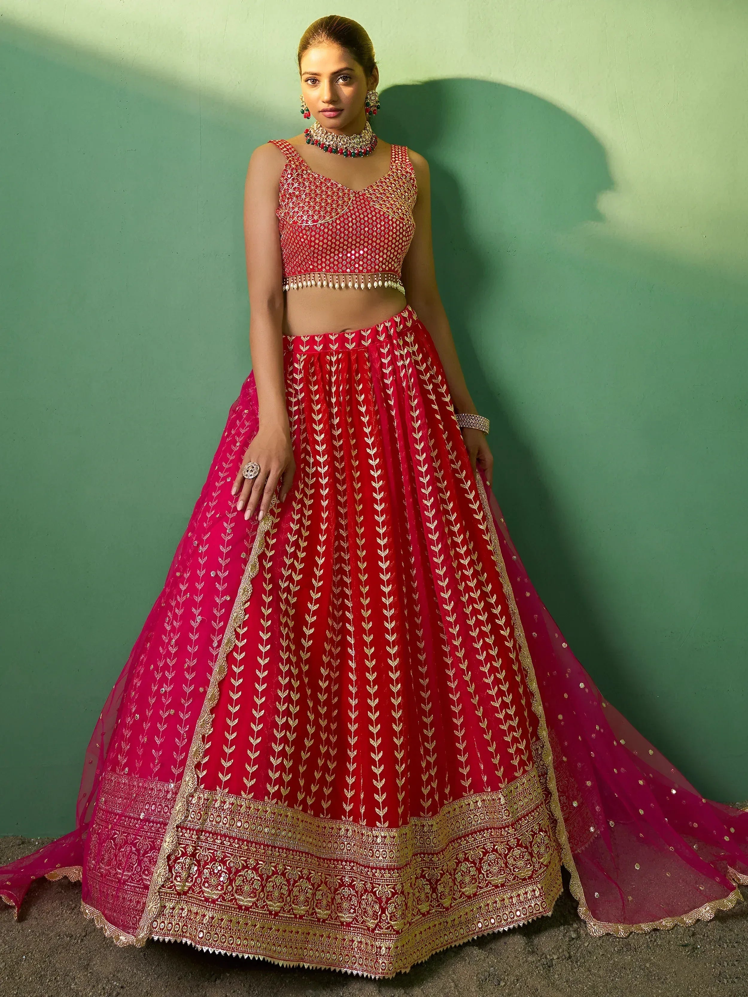 Red and gold embroidered lehenga choli with intricate detailing and matching jewelry