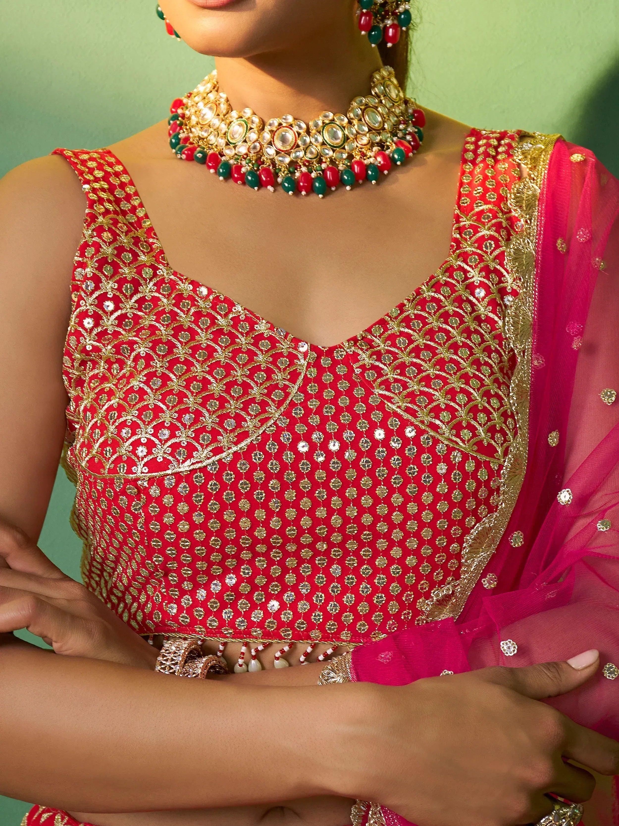 Red and gold embroidered lehenga choli with matching jewelry, perfect for Indian ethnic wear occasions.