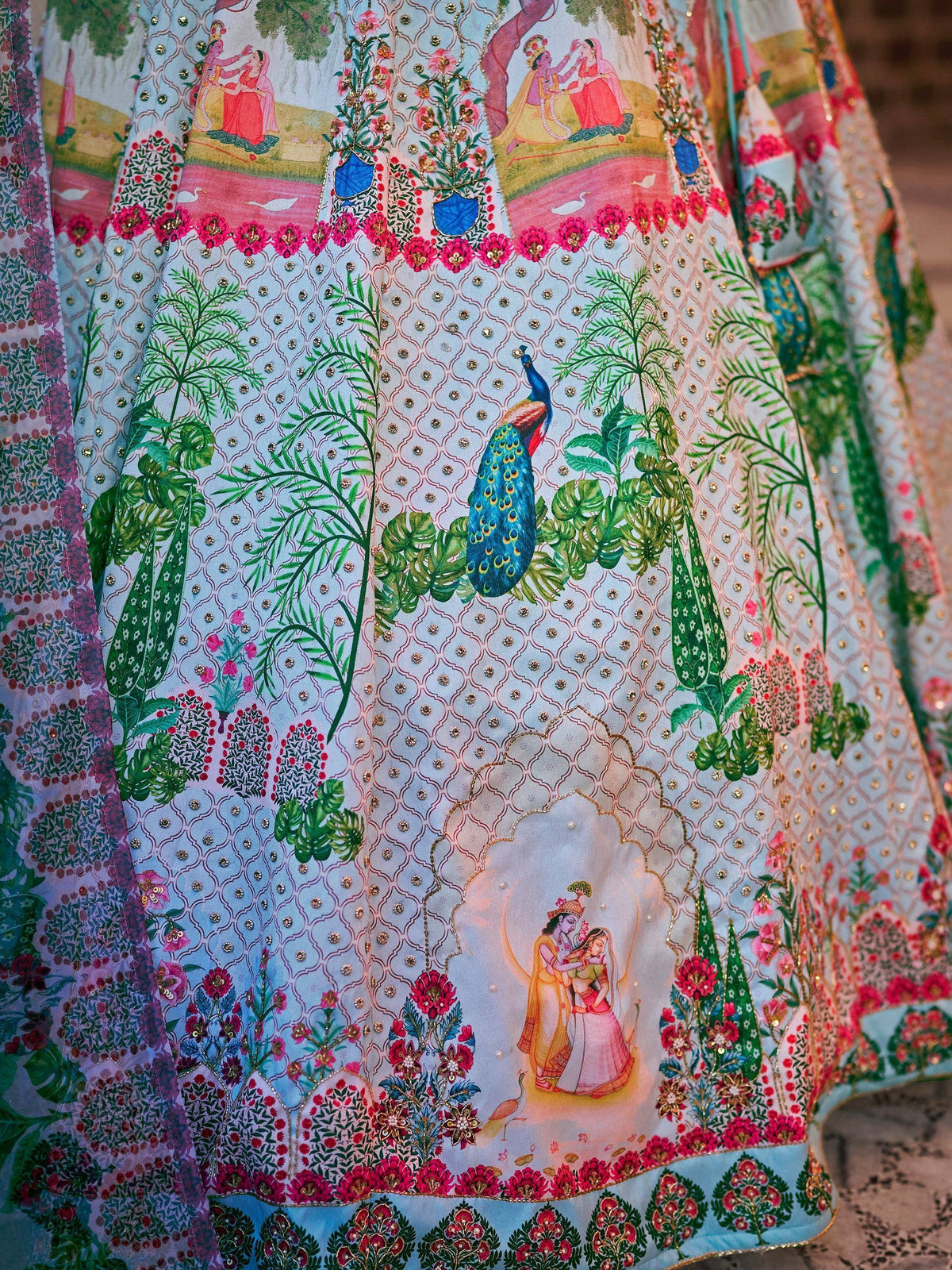 Indian ethnic lehenga with peacock, floral, and deity prints, embellished with sequins and embroidery