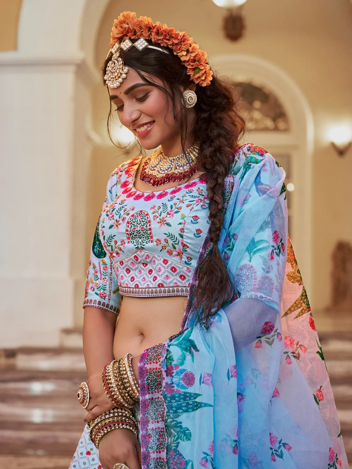 Woman in floral printed blue lehenga choli with gold jewelry and flower crown, Indian ethnic wear