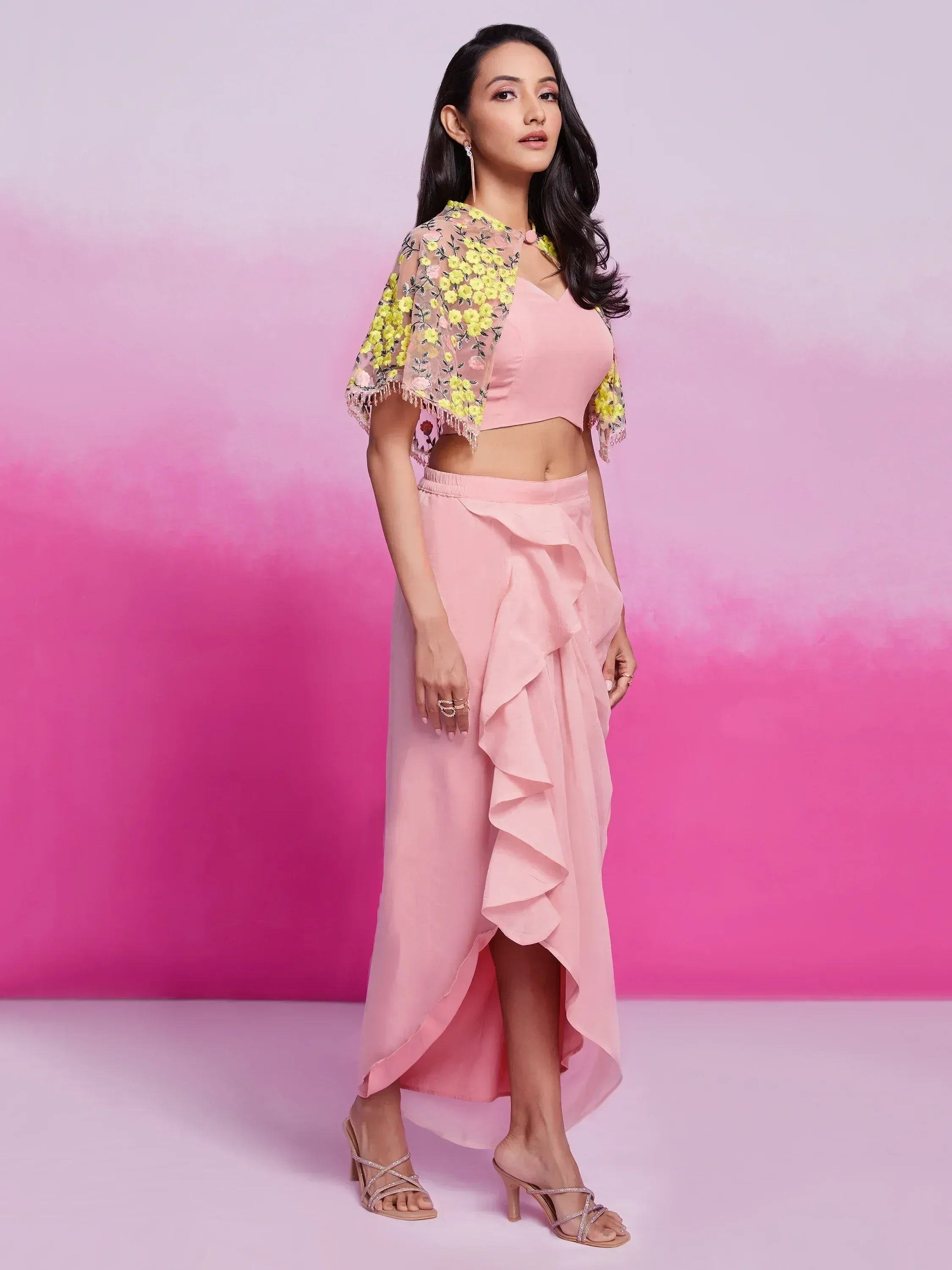 Woman in pink ruffle skirt and crop top with floral embroidered sheer cape, ethnic wear