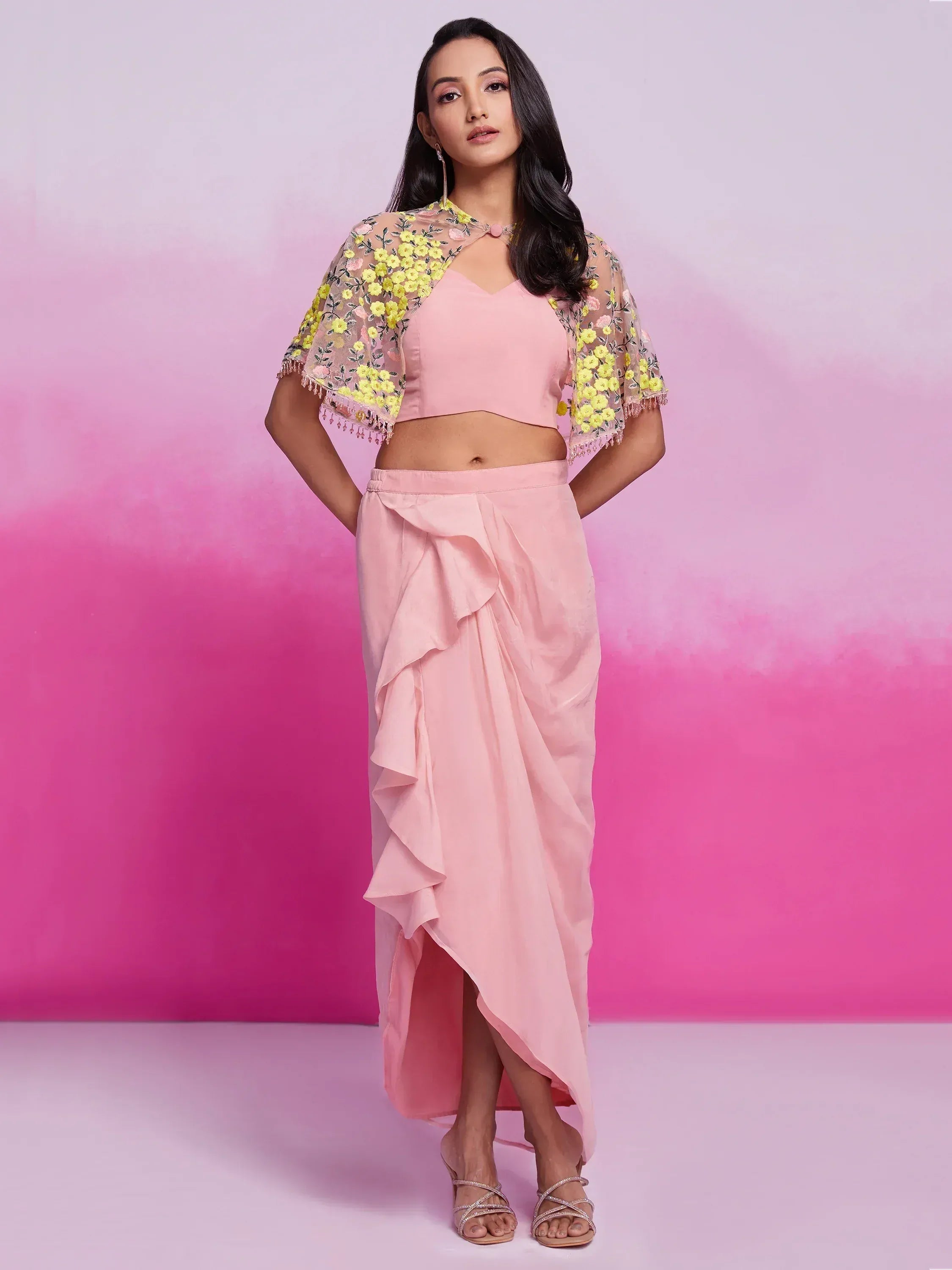 Woman in pastel pink designer lehenga skirt and choli with sheer floral embroidered cape