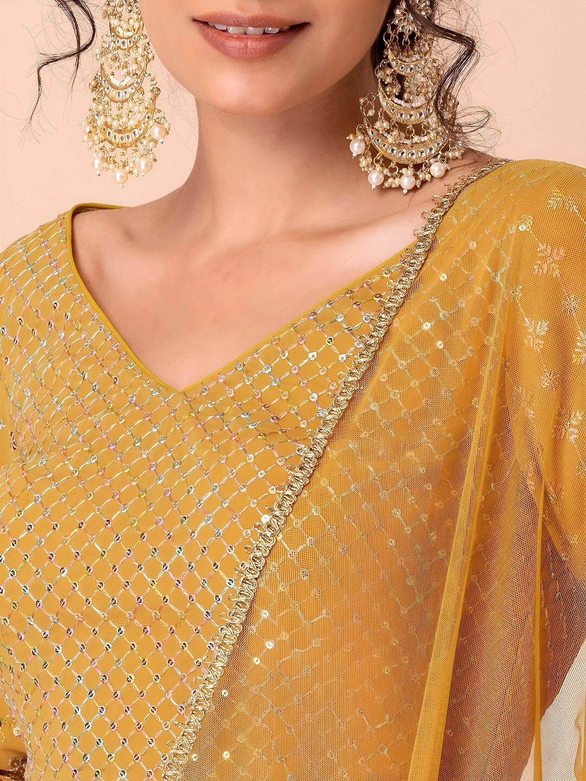 Mustard yellow ethnic gown with sequin mesh overlay and gold embroidery, paired with pearl jhumka earrings