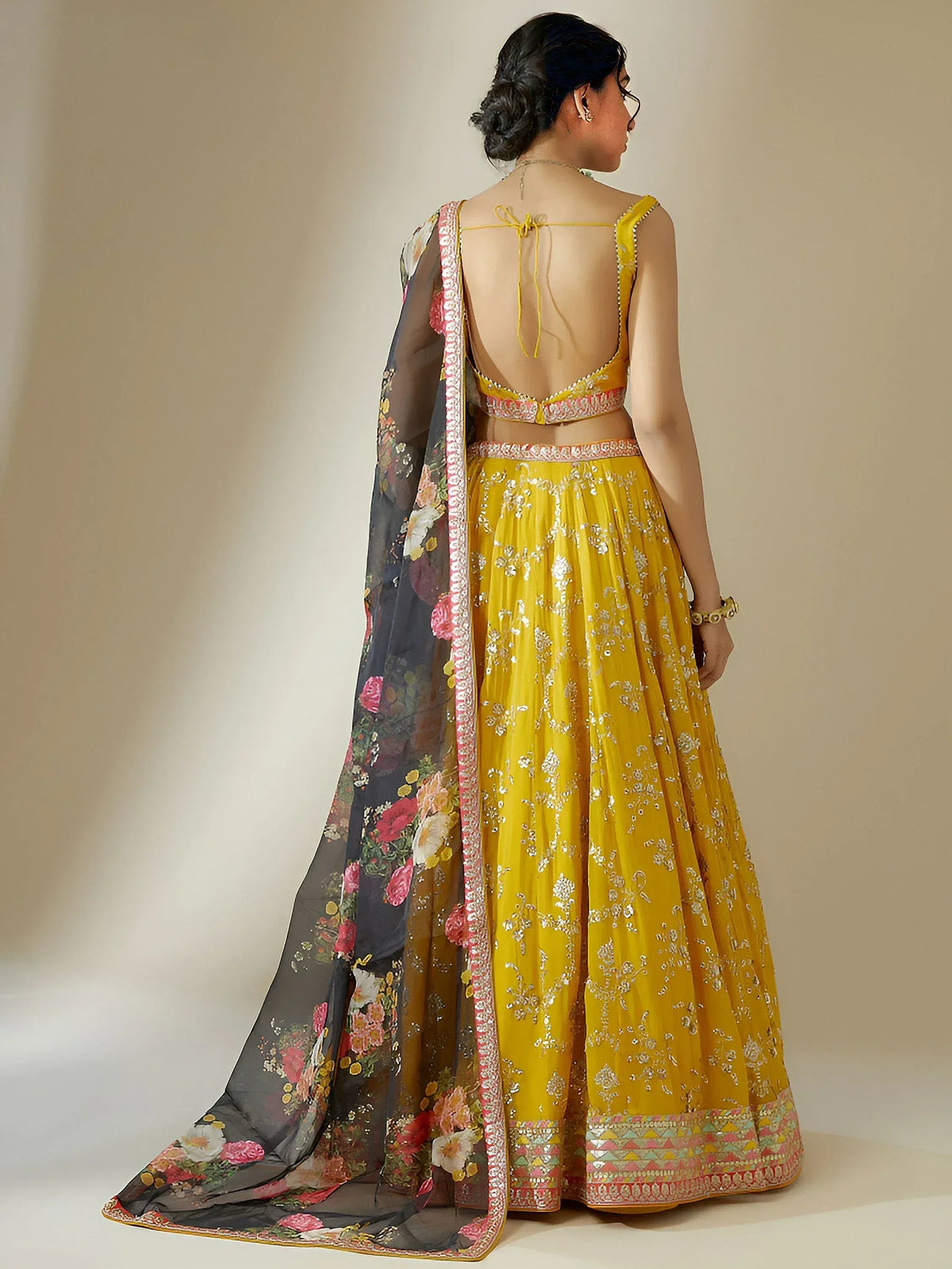 Yellow embroidered lehenga choli with floral dupatta, back view