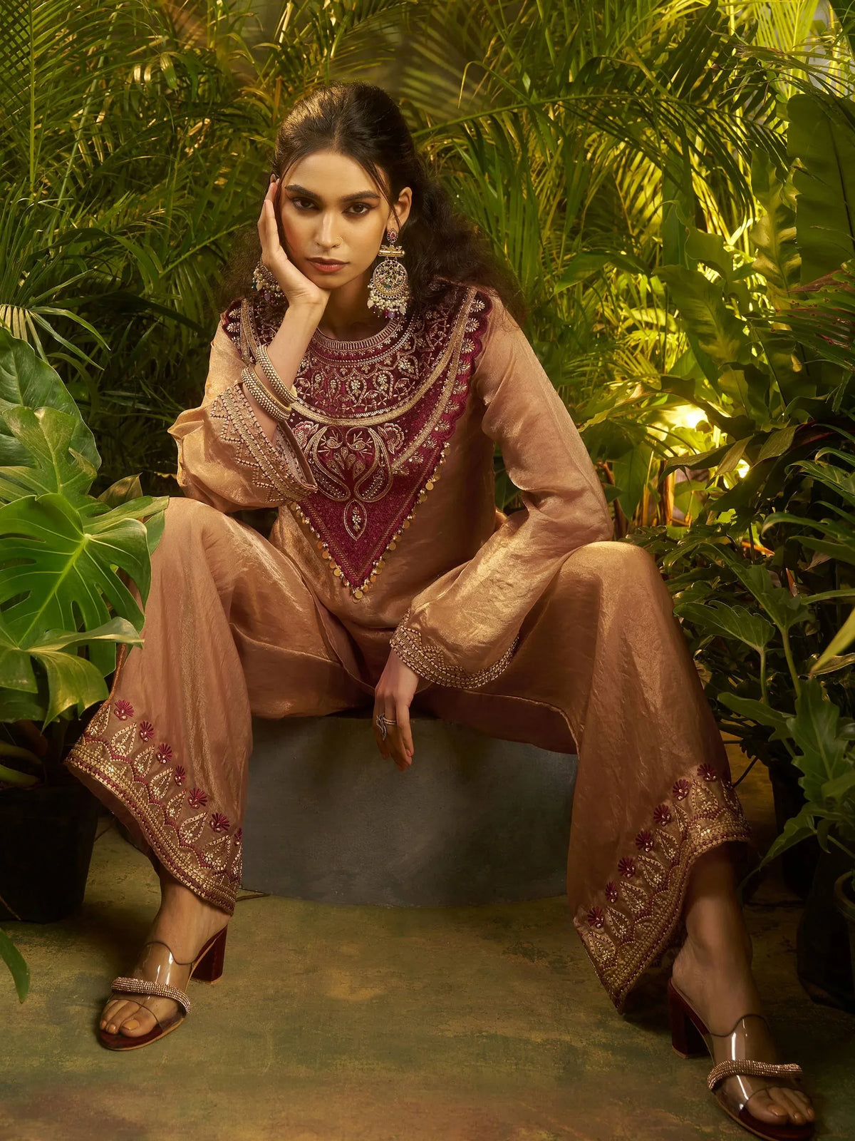 Elegant maroon and gold embroidered salwar kameez with intricate detailing, styled with statement jewelry.