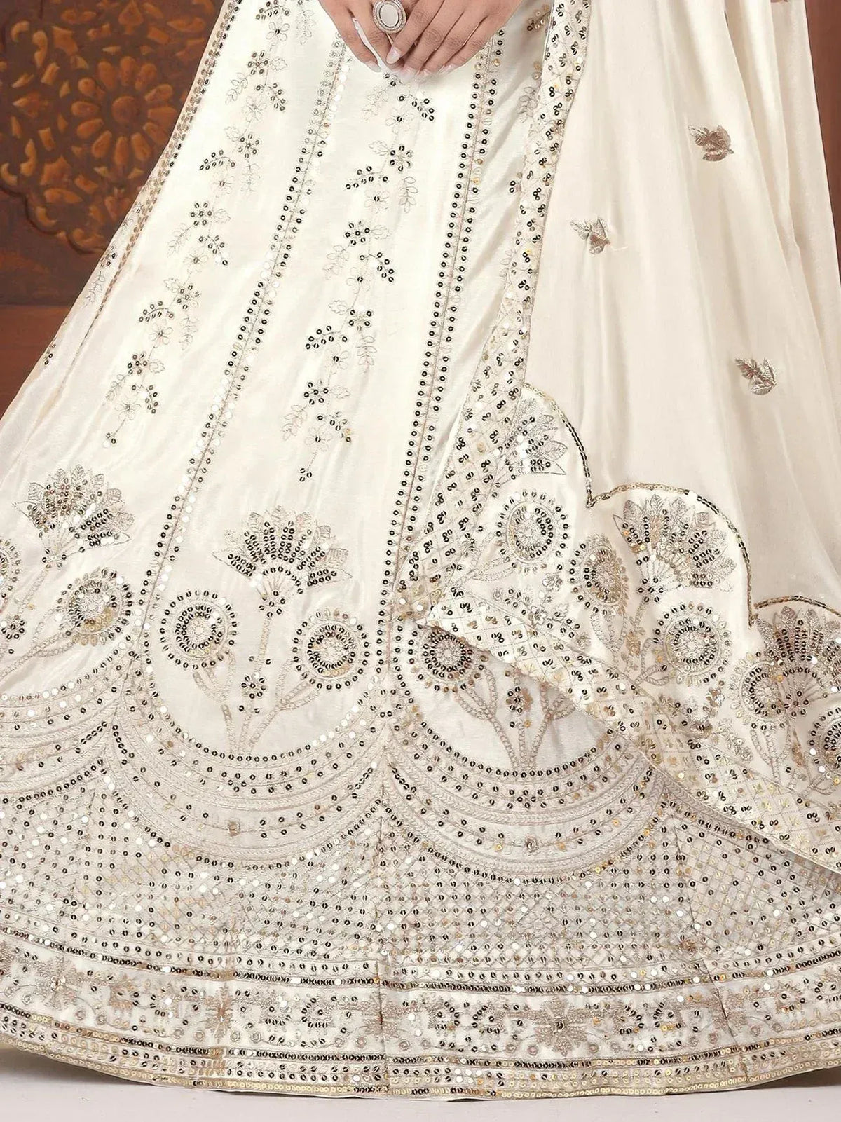 Cream lehenga choli with intricate gold and silver embroidery, mirror work, and floral motifs for Indian ethnic wear.