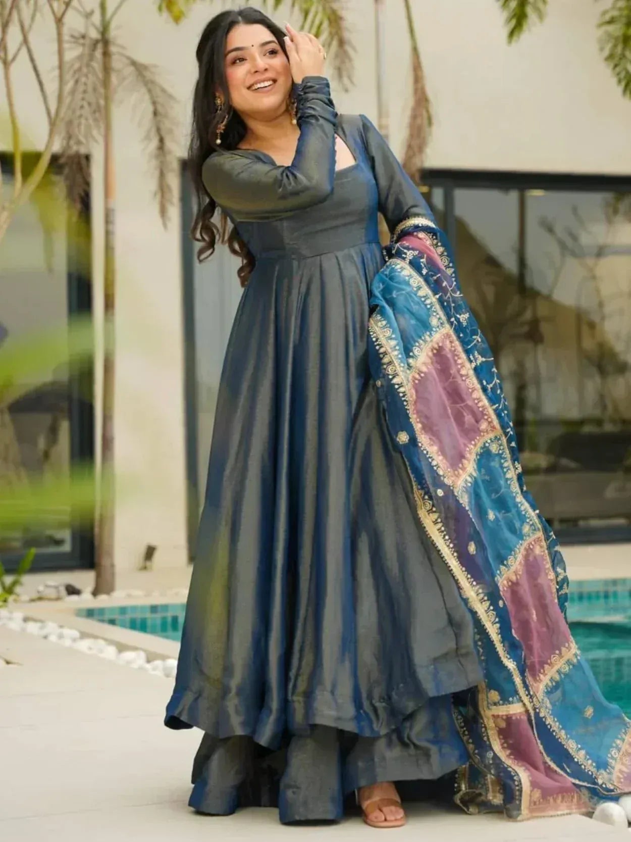Woman in blue ethnic gown with embroidered dupatta, poolside setting