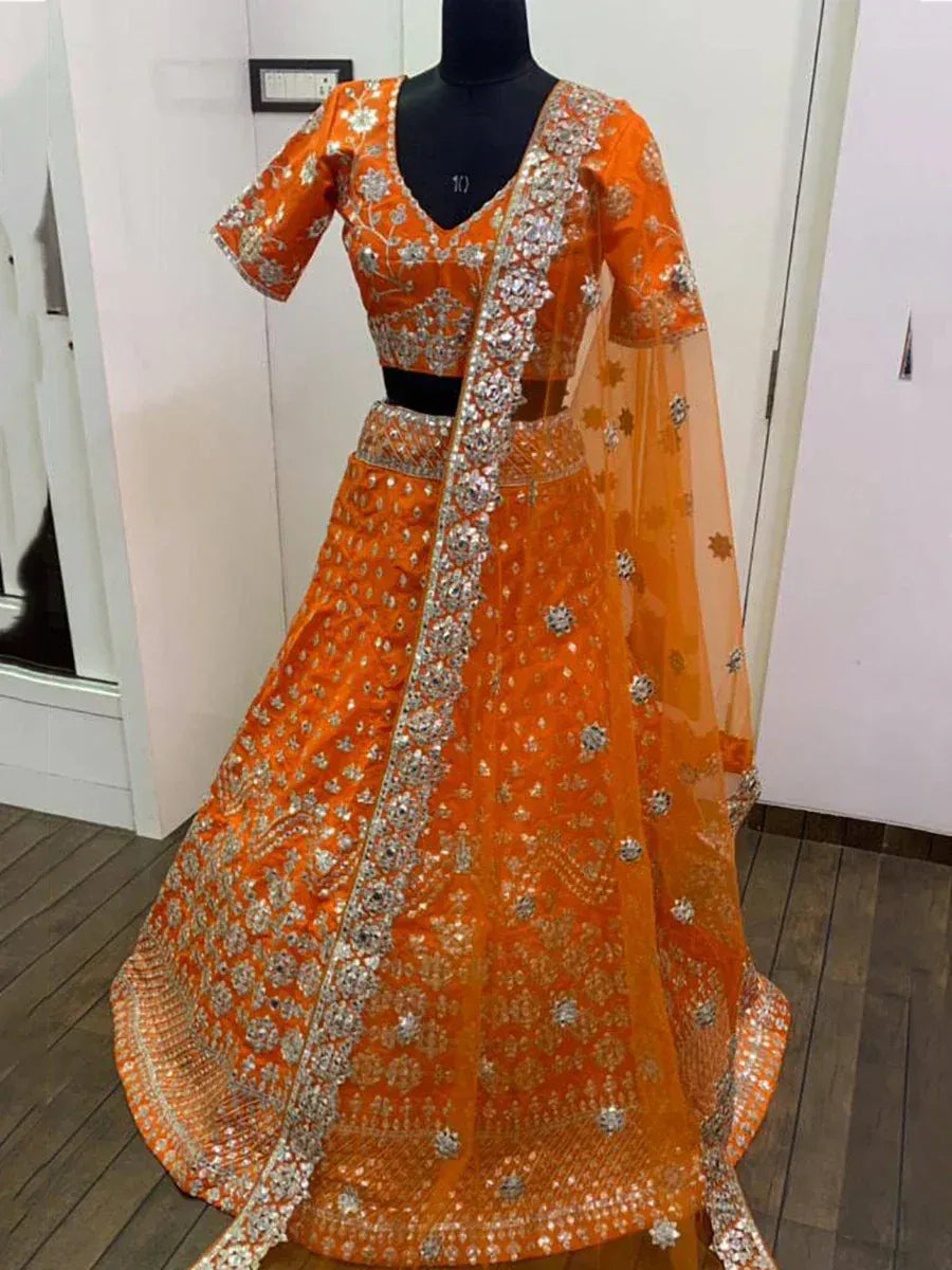 Orange designer lehenga choli with heavy silver embroidery and net dupatta, perfect for Indian weddings and festivals.