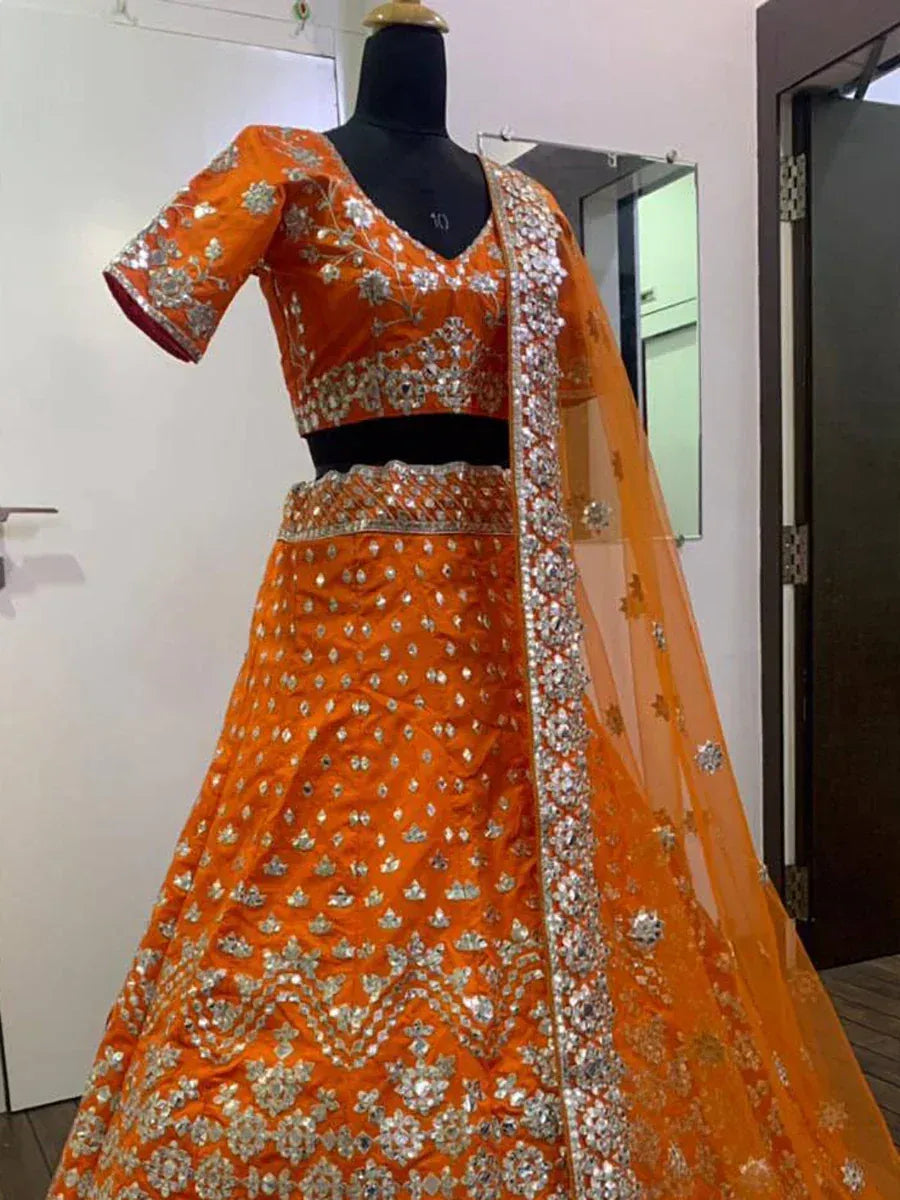 Orange designer lehenga choli with silver embroidery and net dupatta, perfect for Indian weddings and festive occasions.
