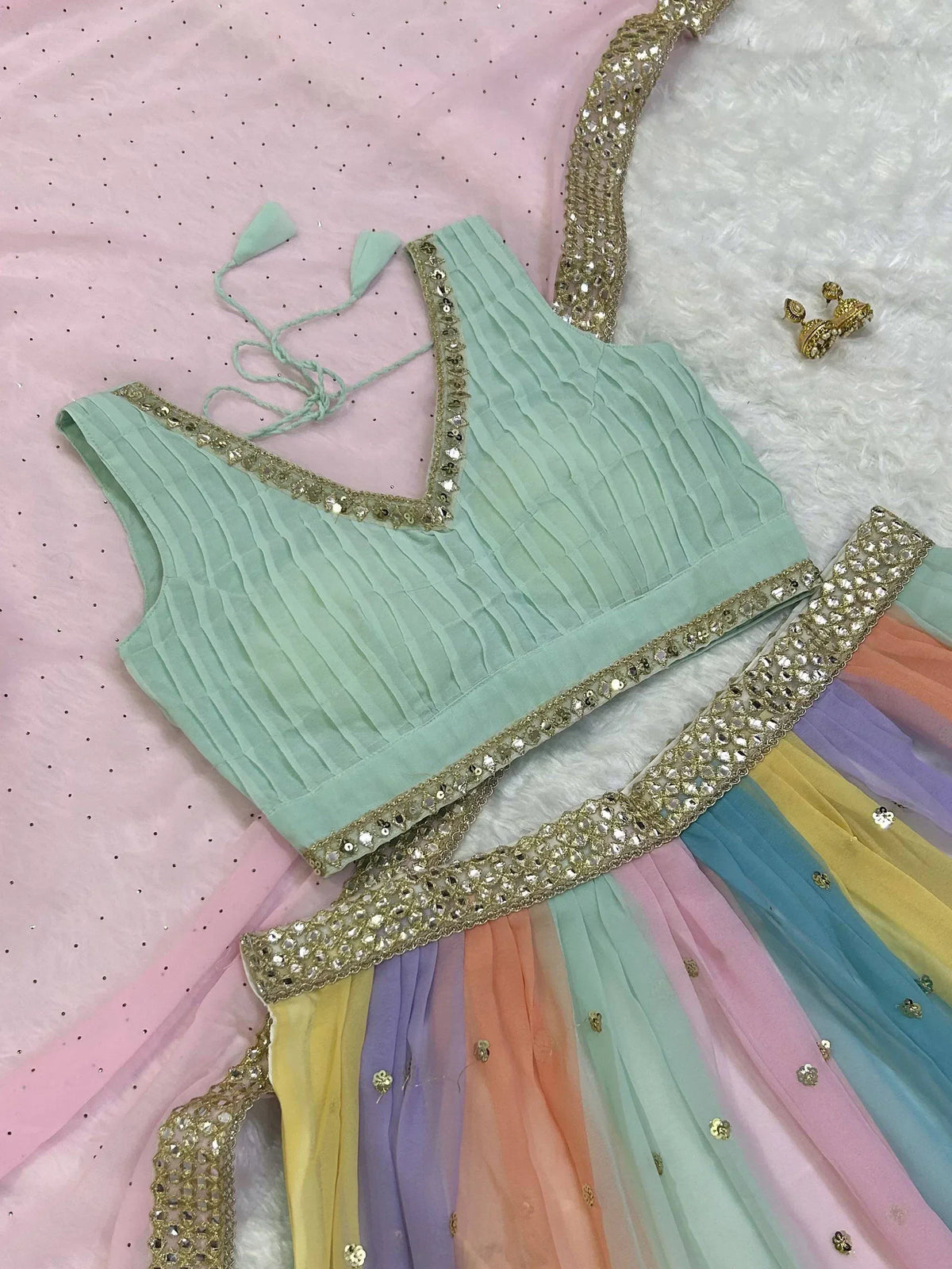 Mint green pleated blouse with rainbow skirt, gold embellishments, and ethnic jewelry