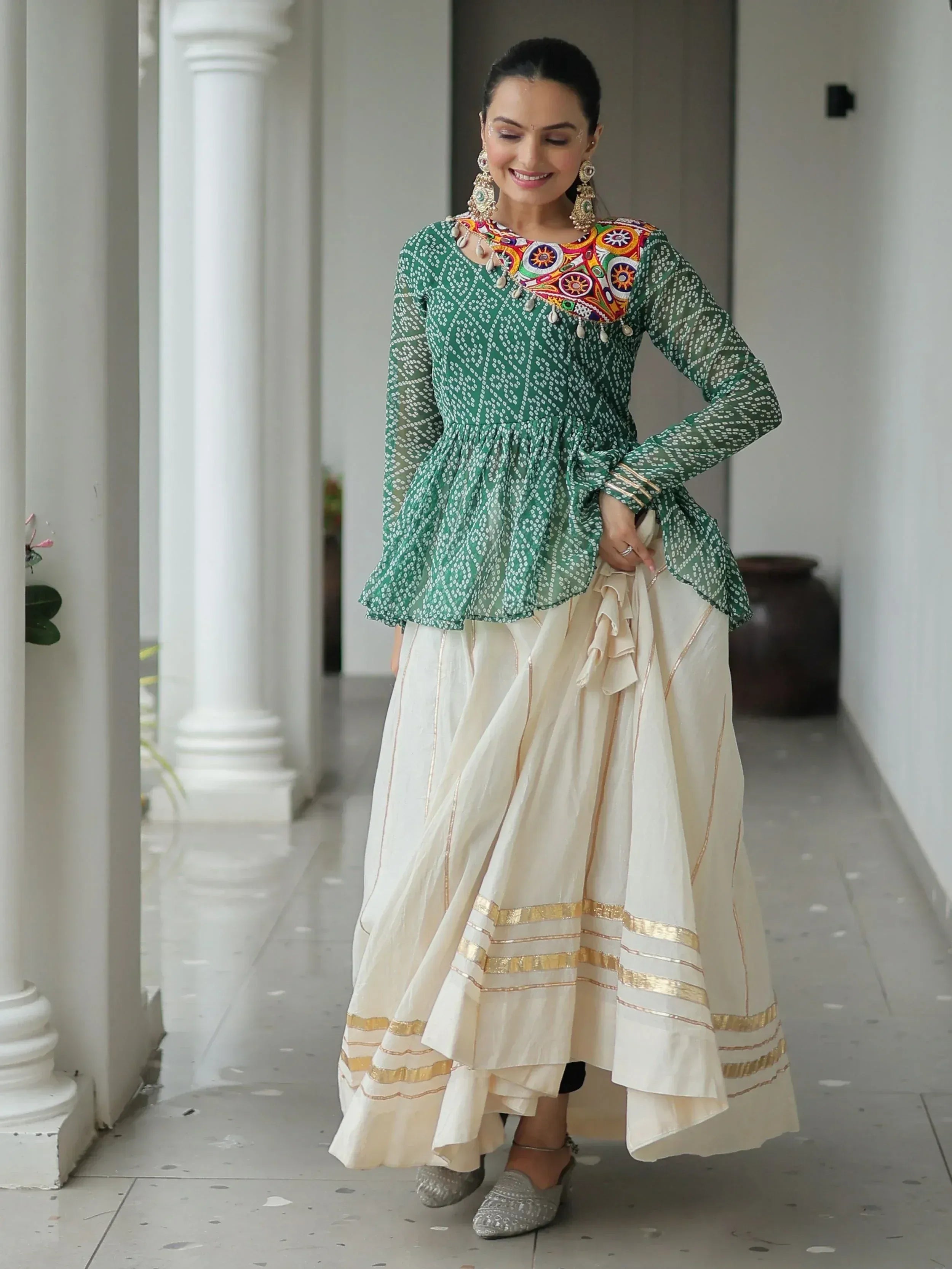 Green printed kurta with colorful embroidery paired with cream skirt featuring gold stripes, styled for Indian ethnic wear.