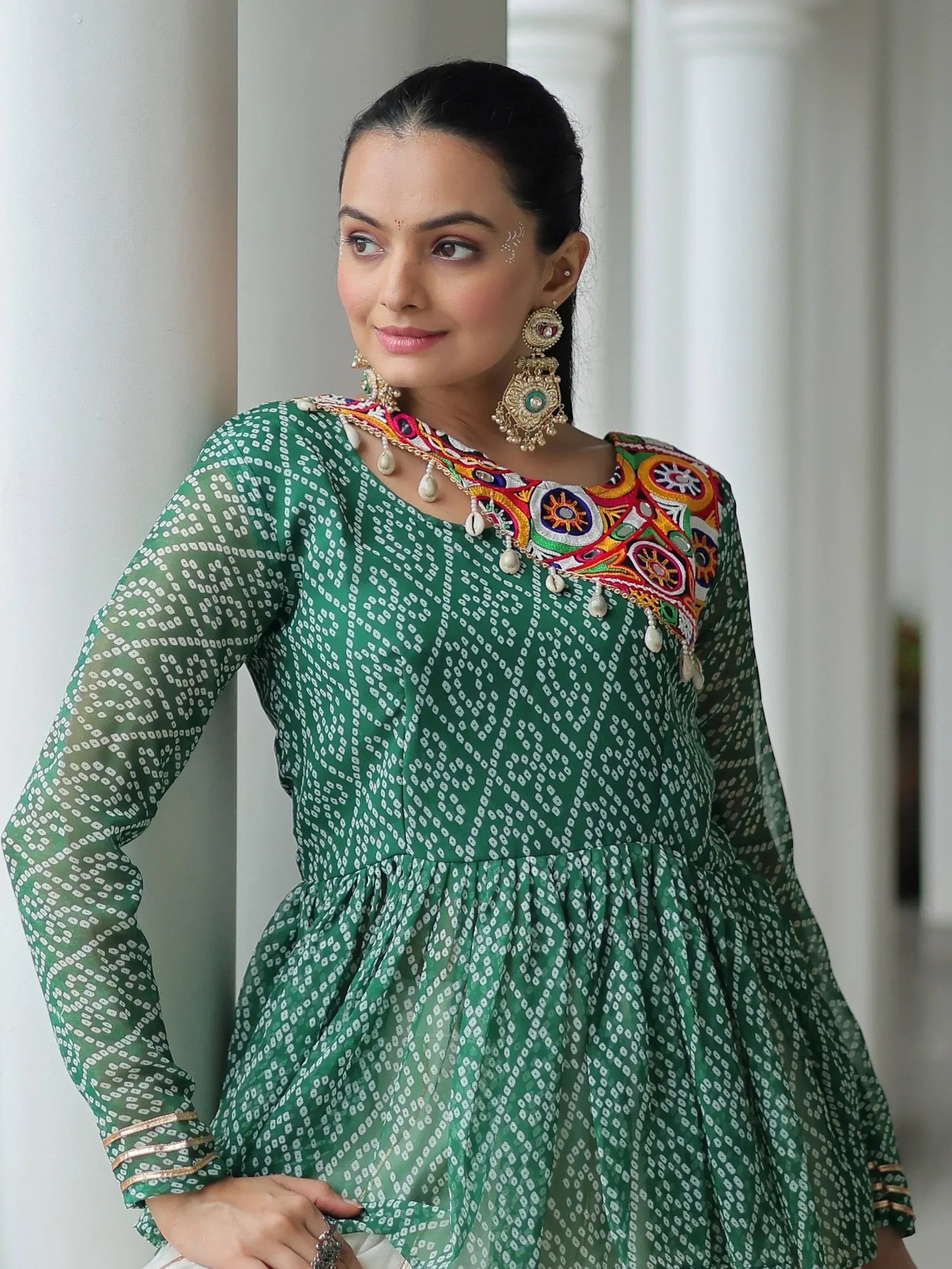 Green printed ethnic gown with colorful embroidery and traditional jewelry