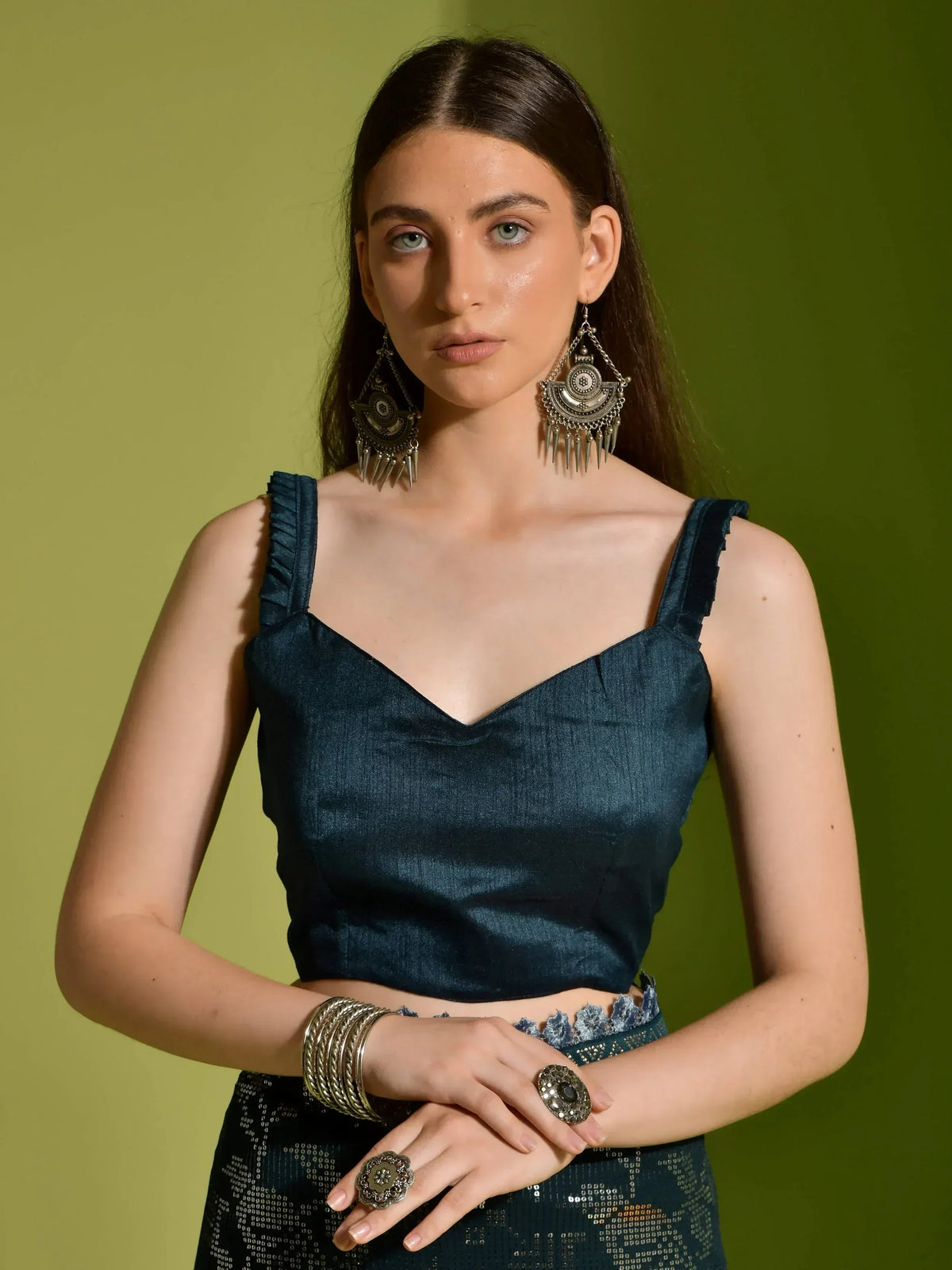 Woman in dark blue ethnic crop top with ruffled straps, paired with embellished skirt and statement earrings