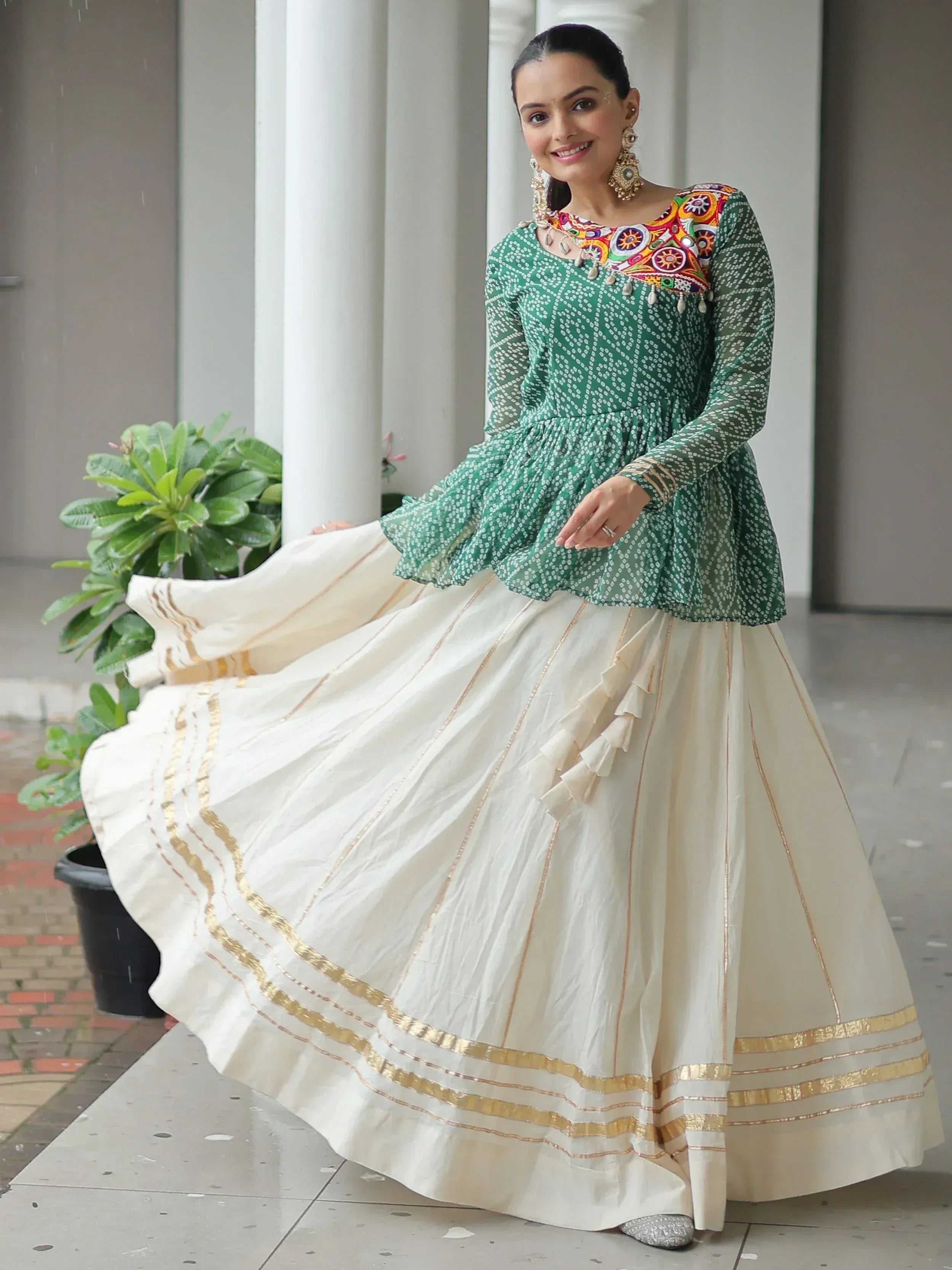 Woman in green embroidered top and cream pleated skirt with gold trim, Indian ethnic wear