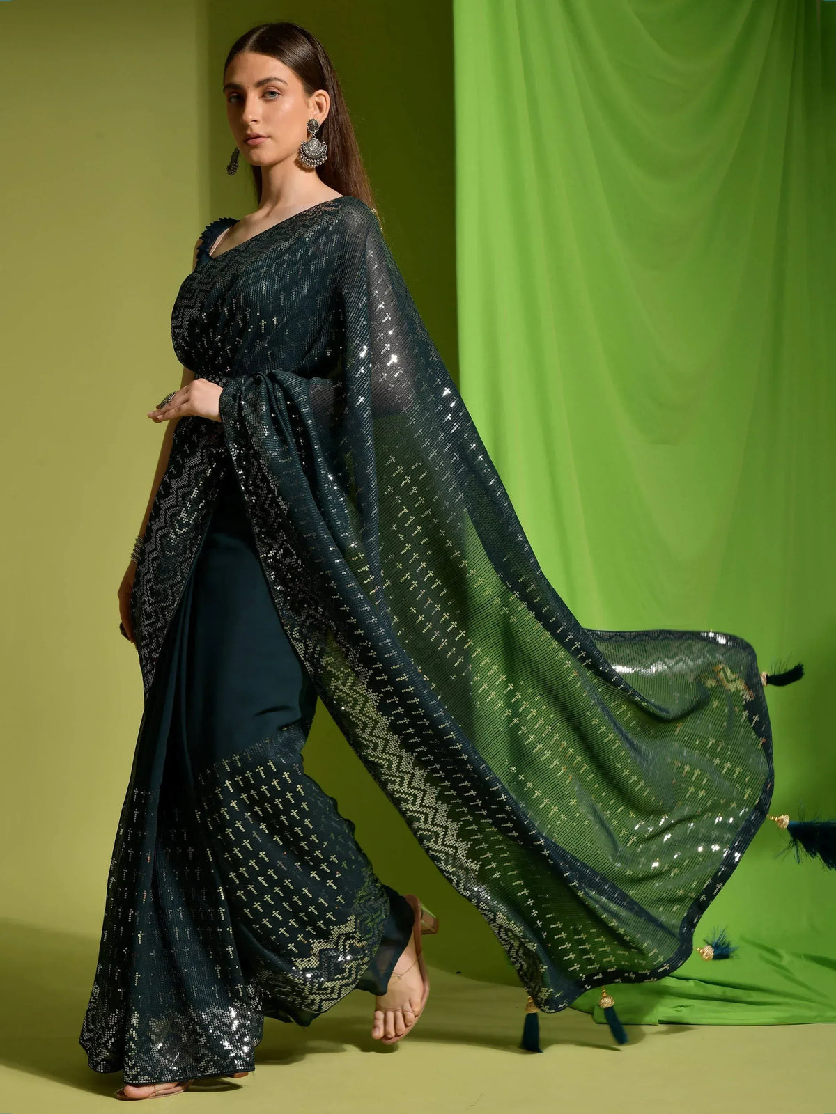 Elegant dark green sequin saree with sheer blouse and tassel detailing, perfect for Indian ethnic occasions.