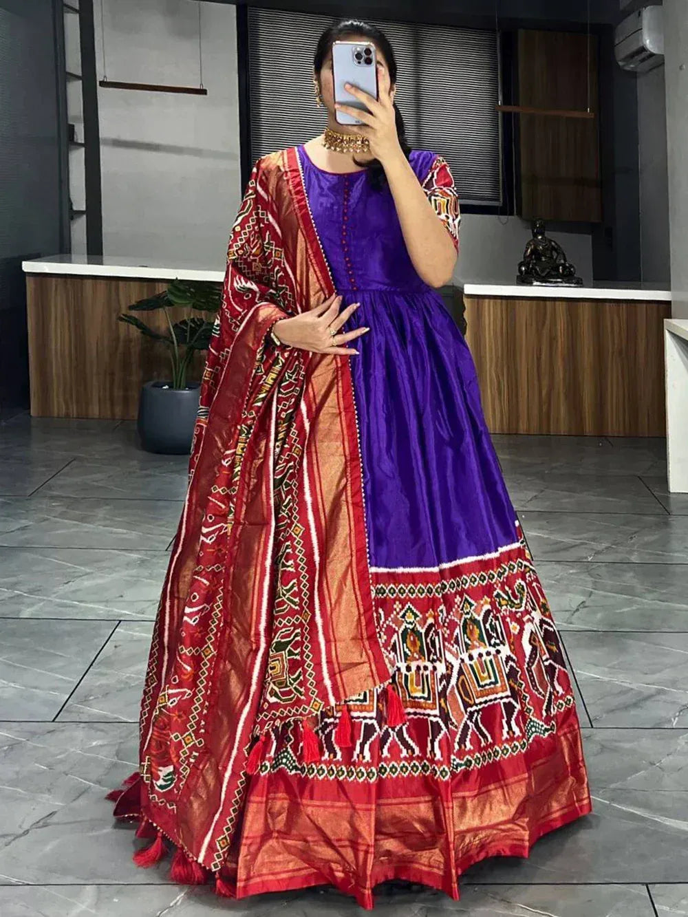 Woman wearing a purple and red traditional Indian lehenga with folk art motifs and dupatta
