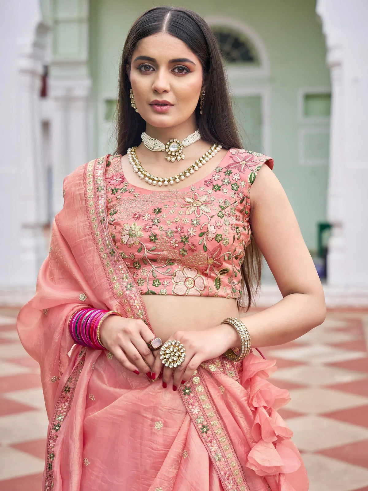 Pink floral embroidered lehenga choli with ruffled skirt and traditional jewelry