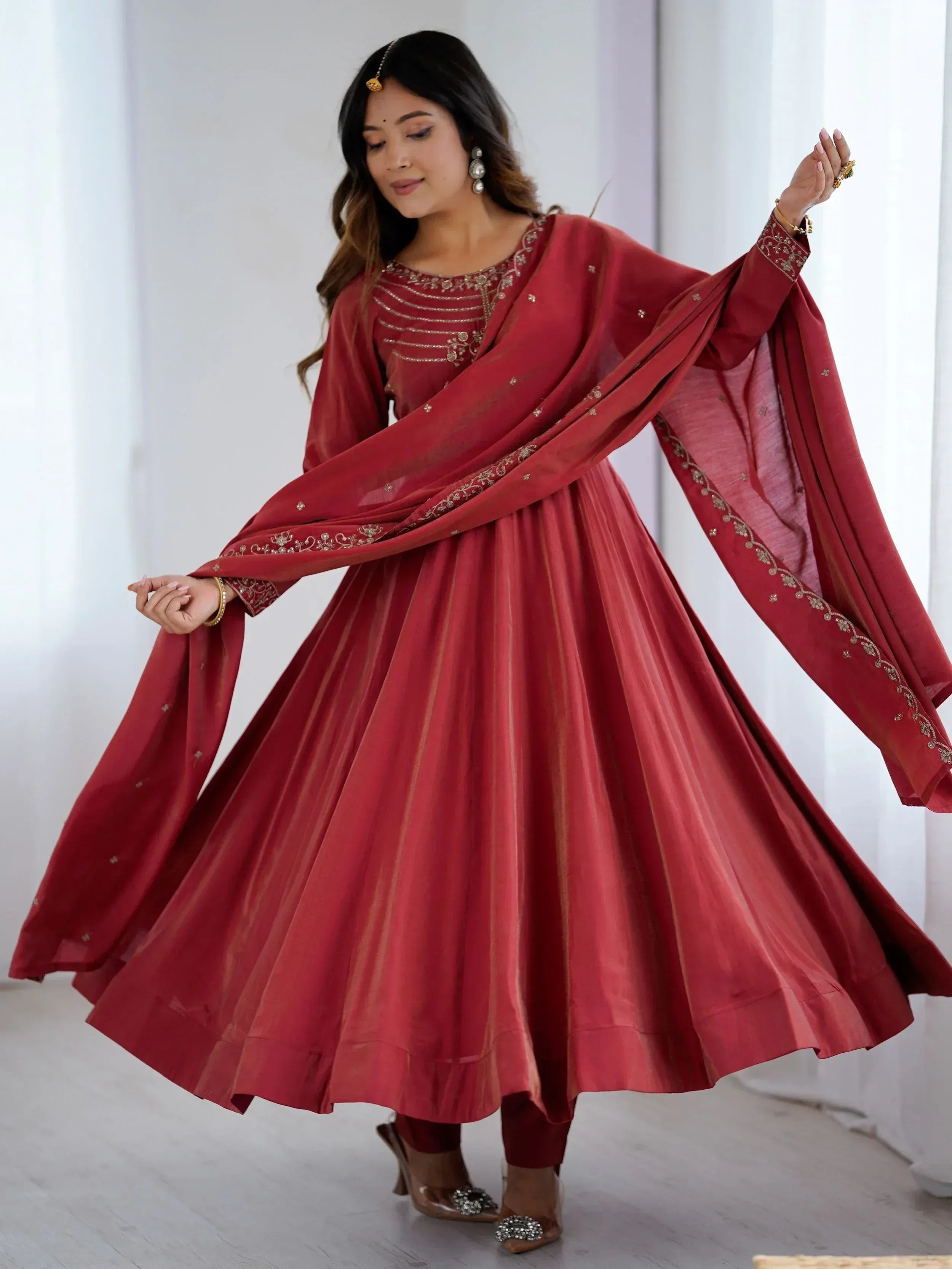 Woman in maroon ethnic anarkali suit with gold embroidery and dupatta, ideal for Indian weddings and festivals