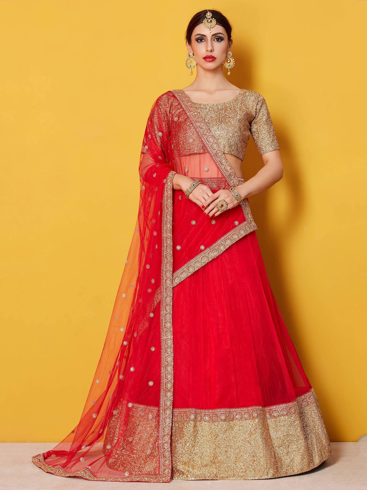 Red and gold designer lehenga choli with intricate embroidery and sheer dupatta, perfect for Indian weddings and festive occasions.