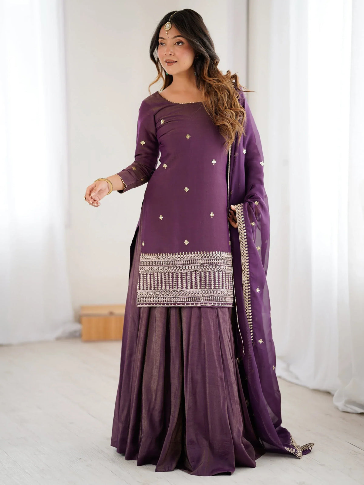 Woman wearing a purple embroidered salwar kameez with a matching dupatta and sharara pants