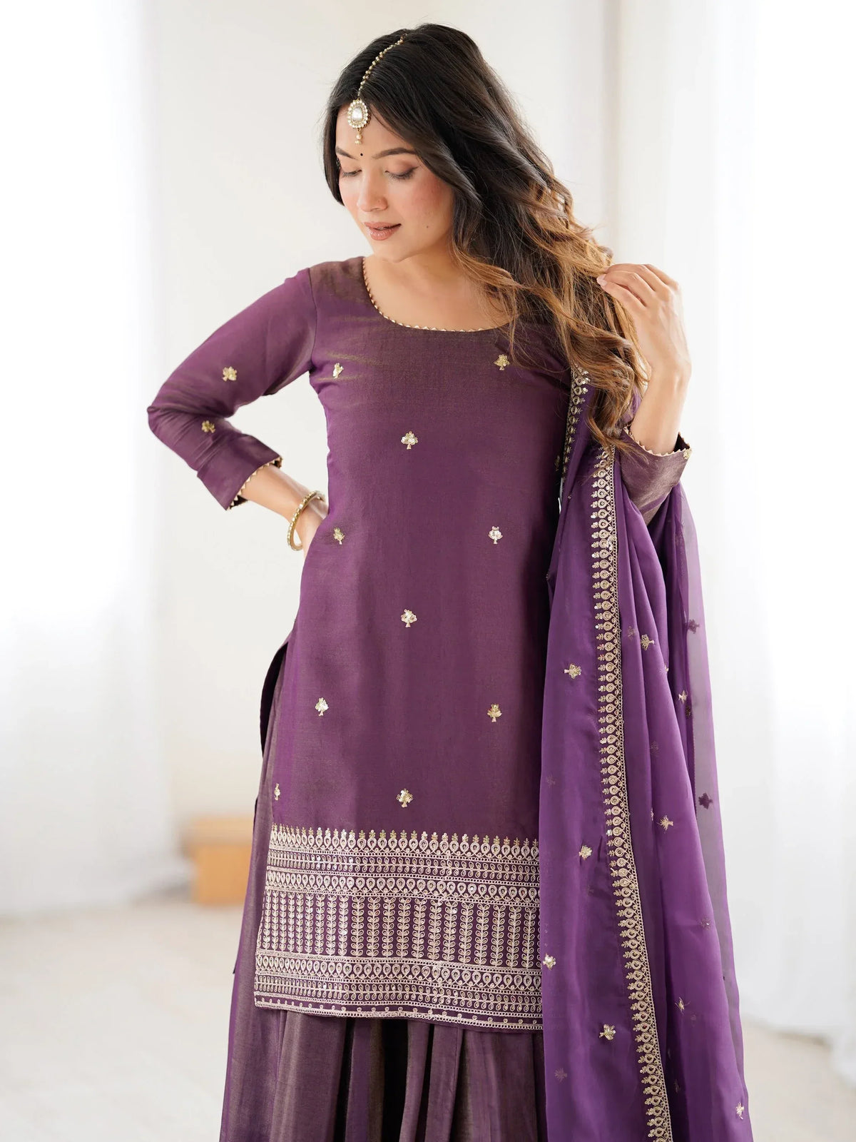Woman wearing a purple embroidered salwar kameez set with a matching dupatta