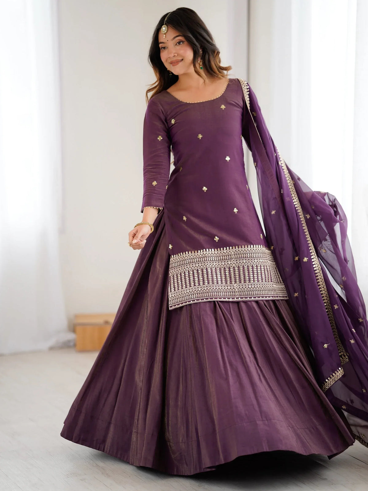 Woman wearing a purple embroidered Indian ethnic kurti and lehenga set with a matching dupatta