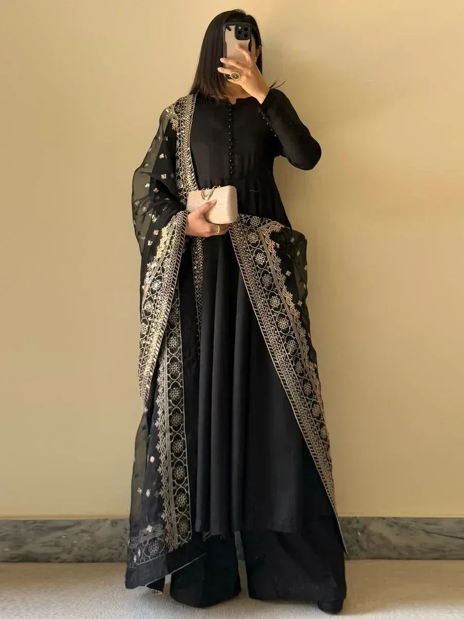 Black ethnic gown with gold embroidery, paired with matching dupatta and palazzo pants for festive occasions