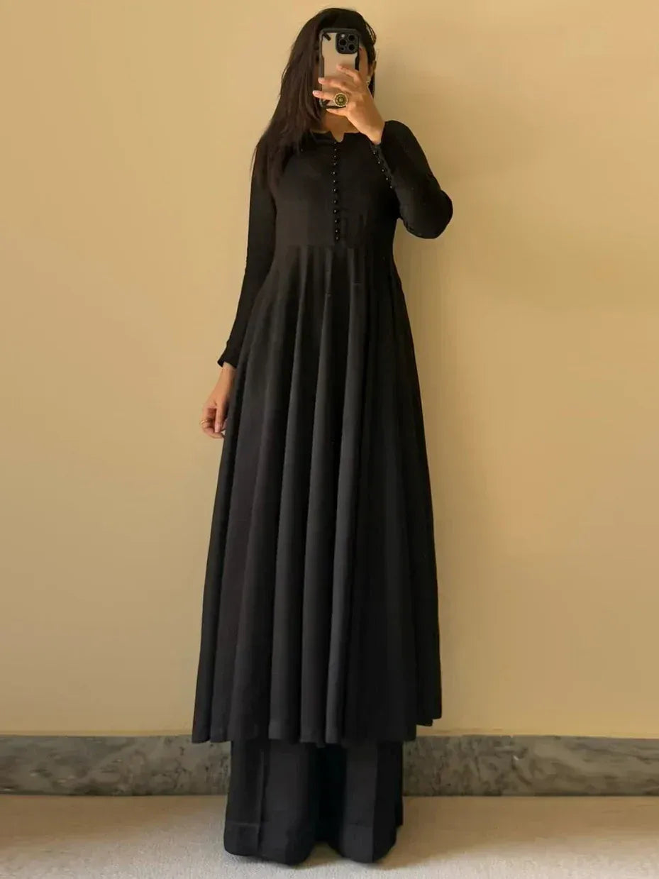Black ethnic gown with long sleeves and pleated skirt, paired with wide-leg pants for modern Indian wear