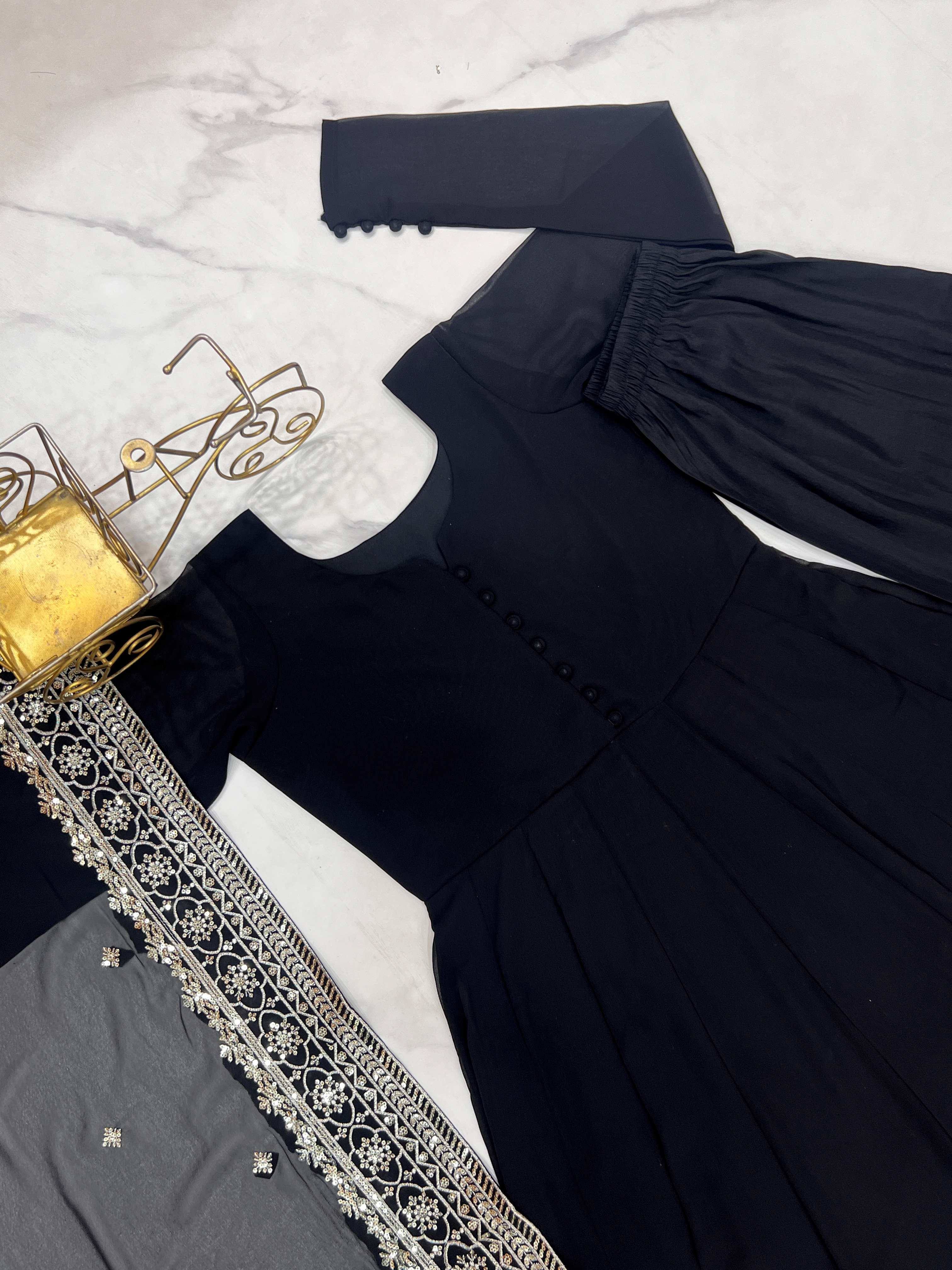 Black ethnic gown with gold embroidery, paired with matching palazzo pants and dupatta, displayed on marble.