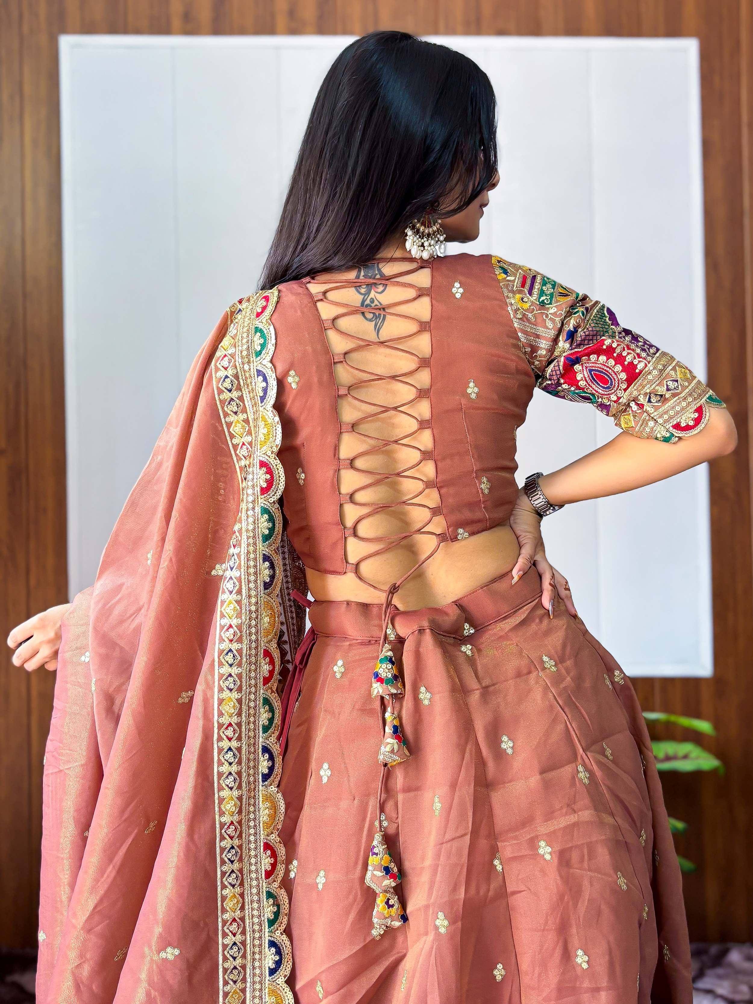 Back view of woman in dusty rose lehenga choli with lace-up back, embroidered dupatta, and colorful detailing
