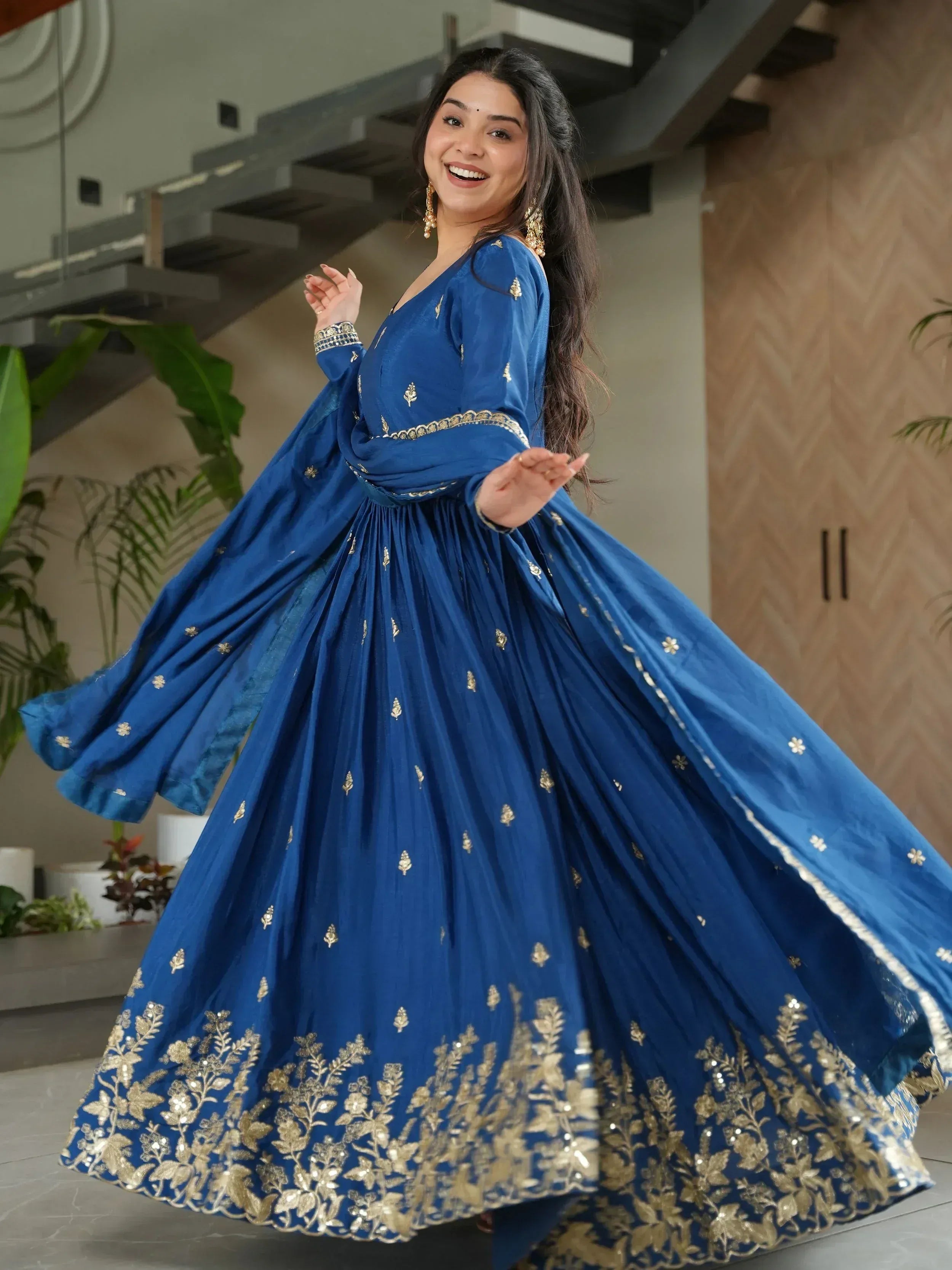 Woman in royal blue ethnic gown with gold embroidery, perfect for Indian occasions and festive wear.