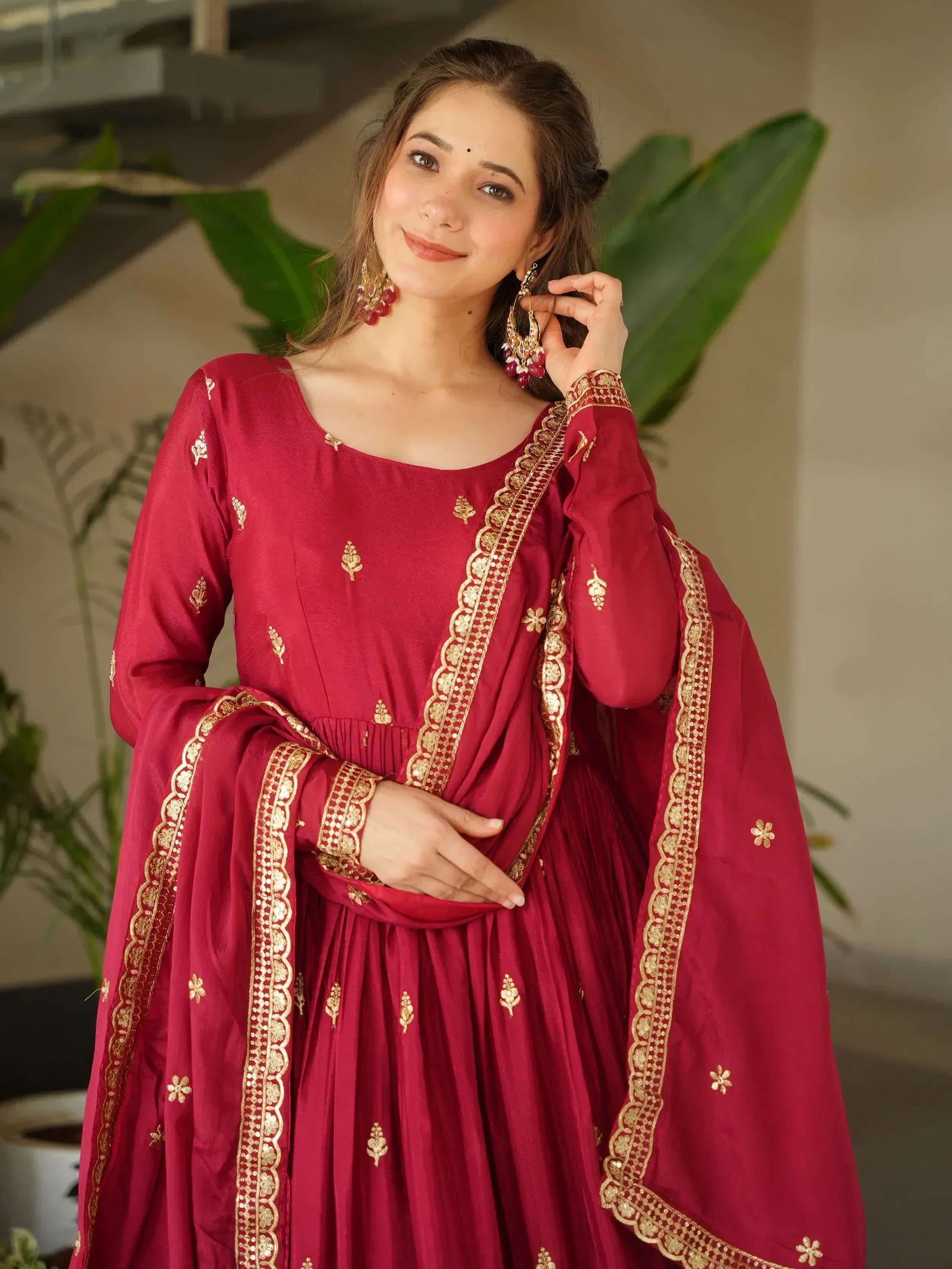 Maroon ethnic gown with gold embroidery and embellished border, perfect for Indian occasions