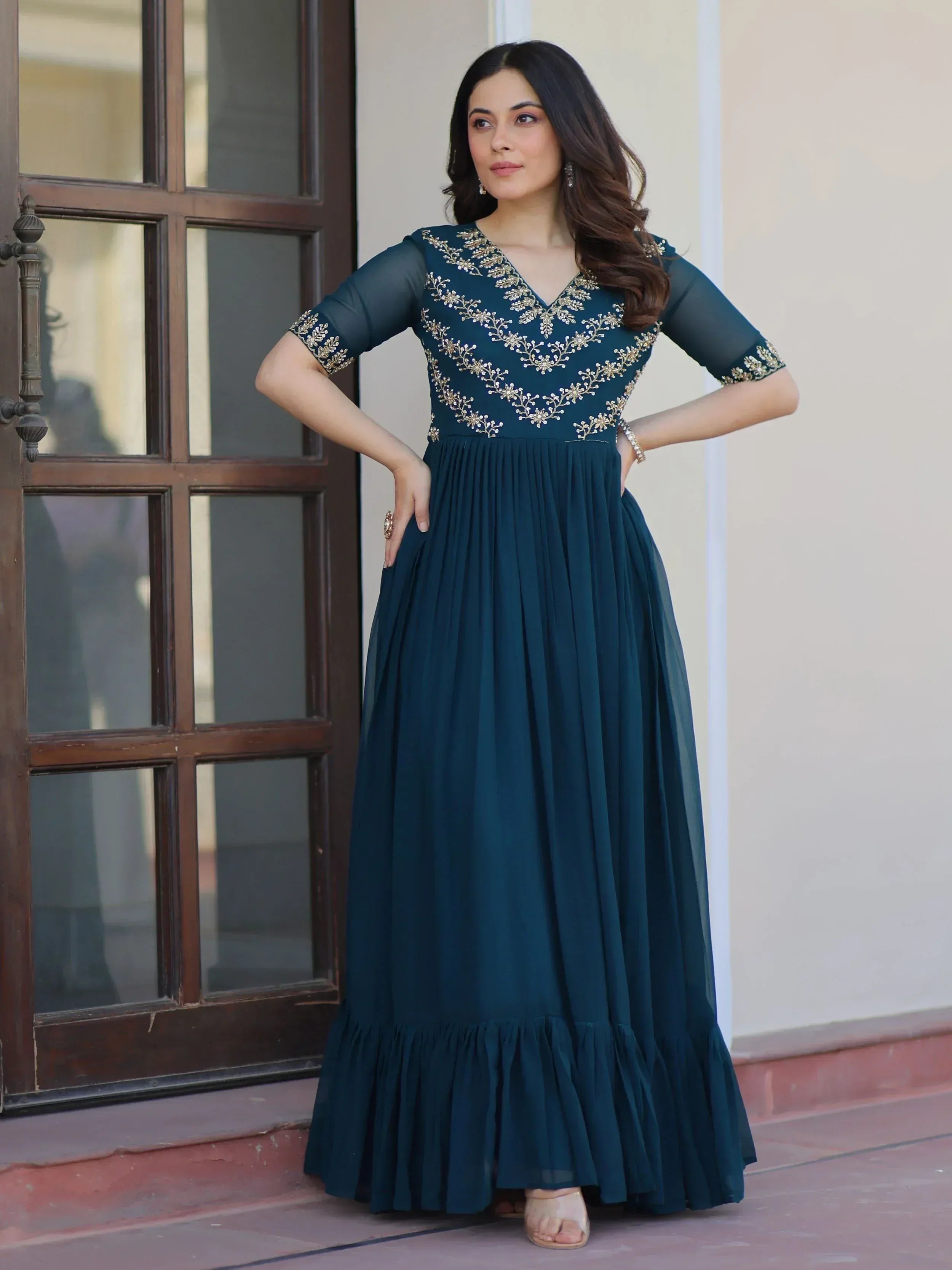 Teal ethnic gown with gold embroidery, sheer sleeves, and pleated skirt for Indian wear