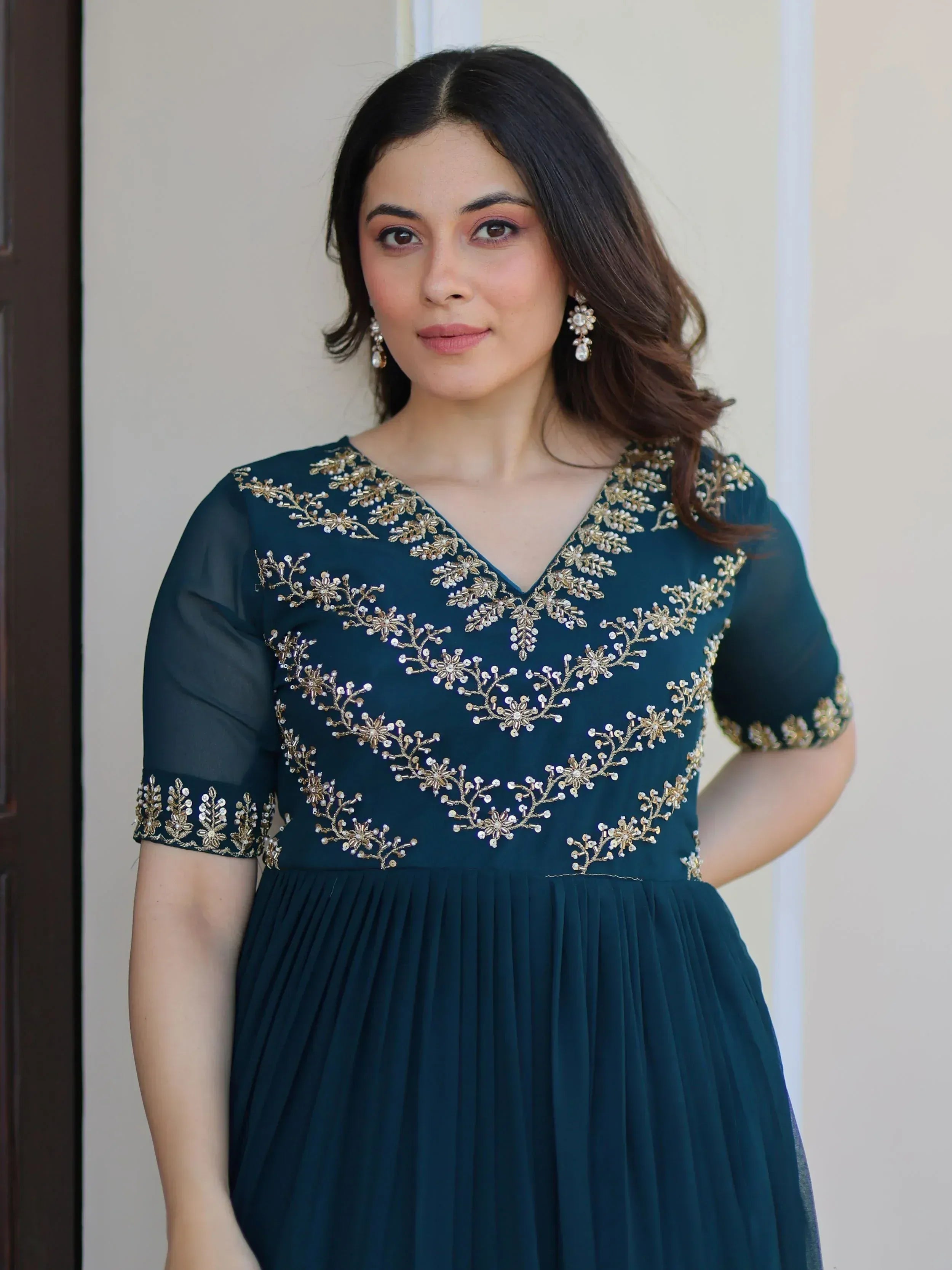 Teal ethnic gown with gold floral embroidery and sheer sleeves, perfect for Indian occasions.