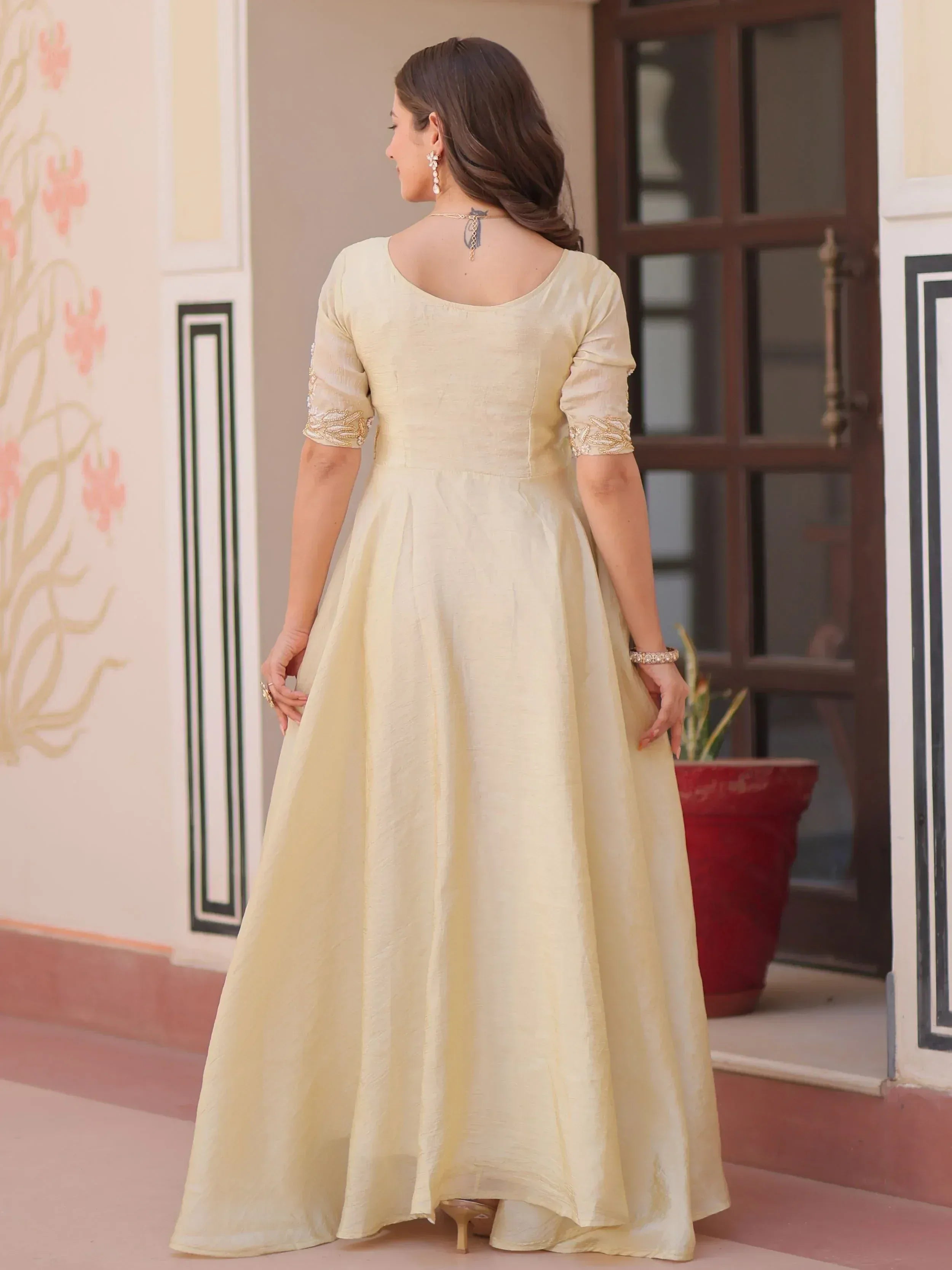 Elegant cream ethnic gown with embroidered sleeves, perfect for Indian occasions and festive wear.