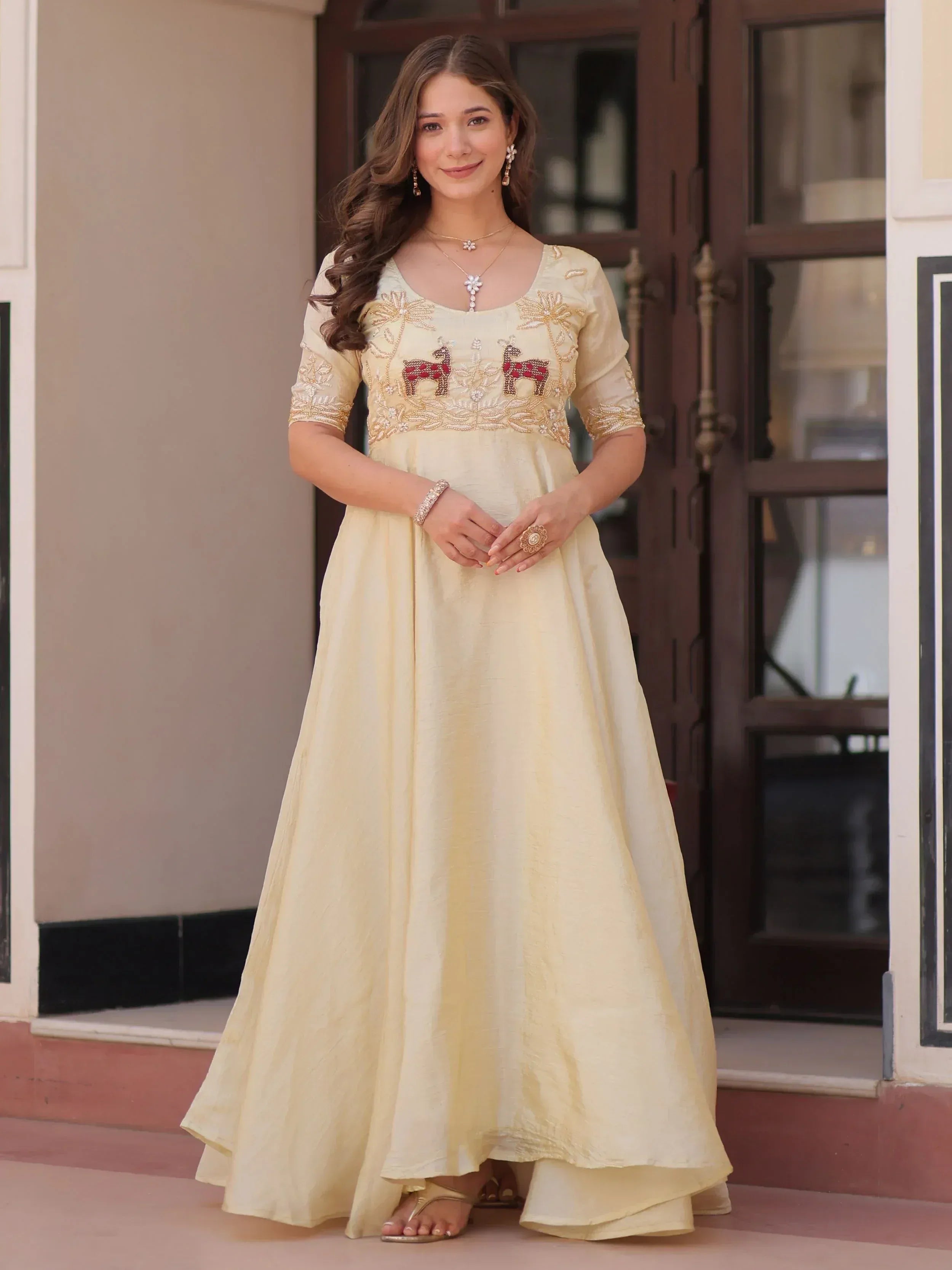Cream ethnic gown with embroidered deer motifs, perfect for Indian occasions and festive wear.