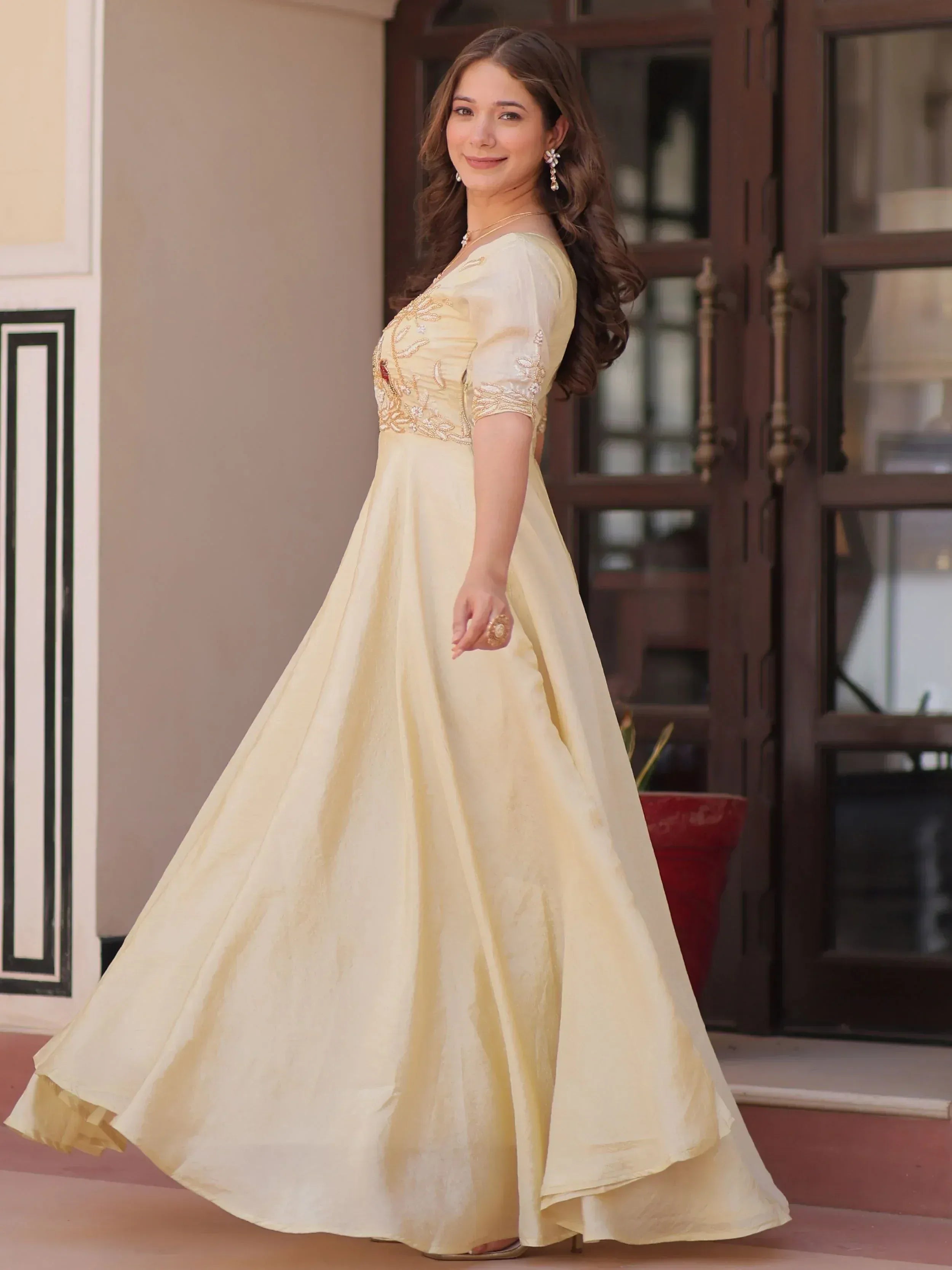 Elegant cream ethnic gown with gold embroidery, perfect for Indian weddings and festive occasions.