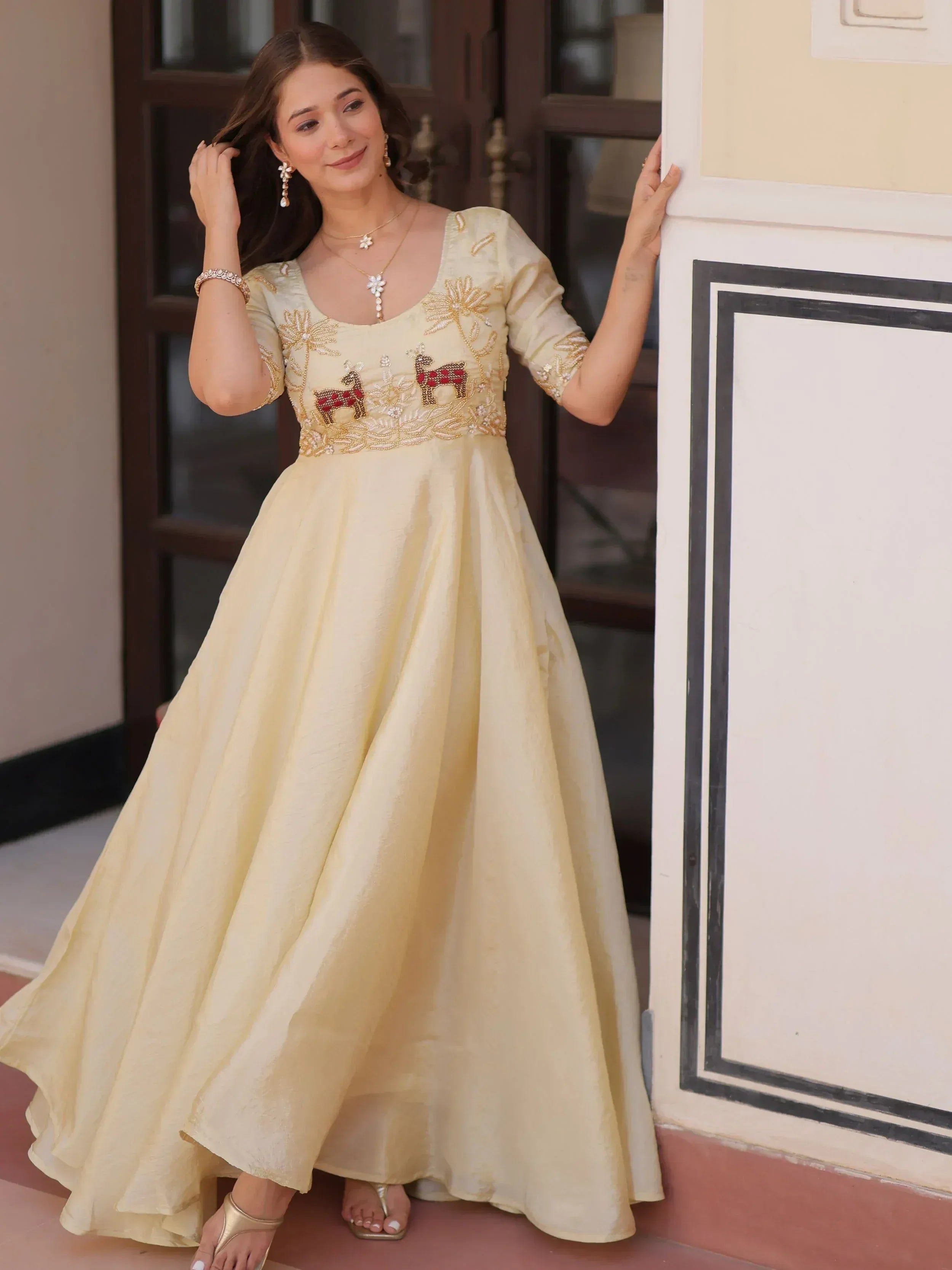 Elegant cream ethnic gown with floral and deer embroidery, perfect for Indian festive occasions