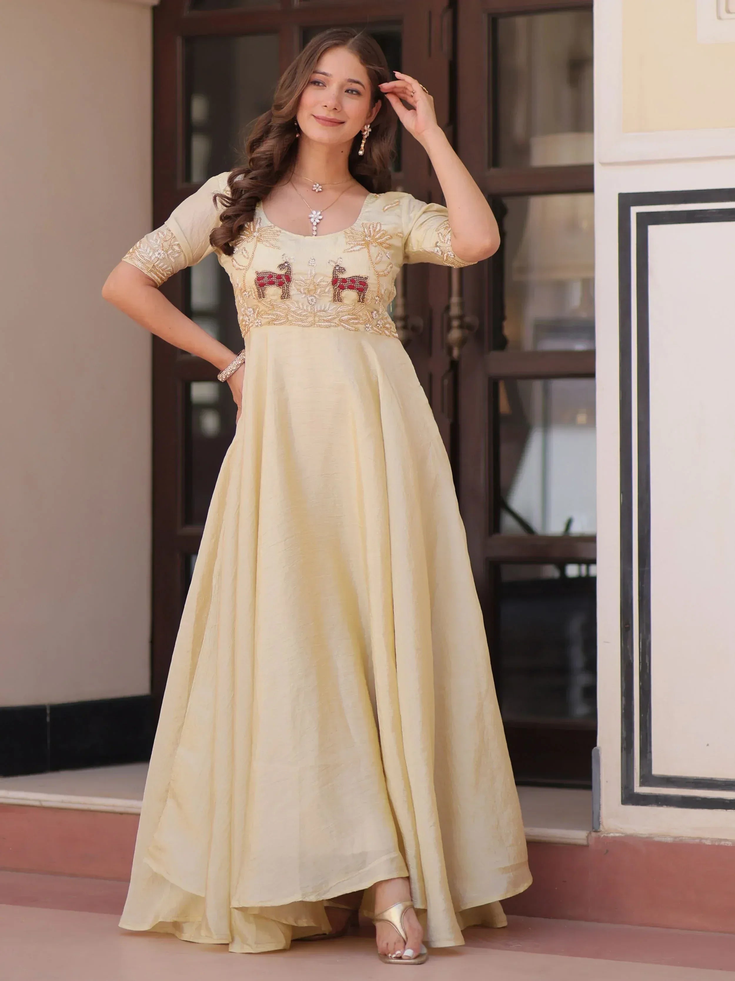 Elegant cream ethnic gown with embroidered deer motifs, perfect for Indian festive occasions and weddings.