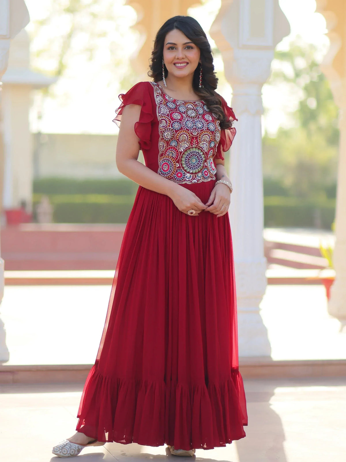 Red ethnic gown with intricate embroidery and ruffled sleeves for festive occasions