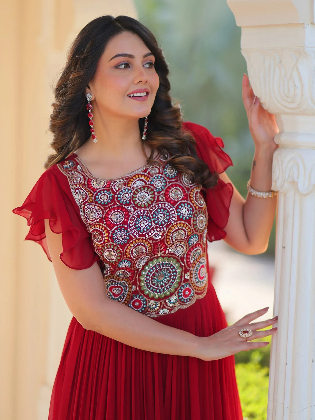Red embroidered ethnic gown with ruffled sleeves and colorful beadwork, perfect for festive occasions.