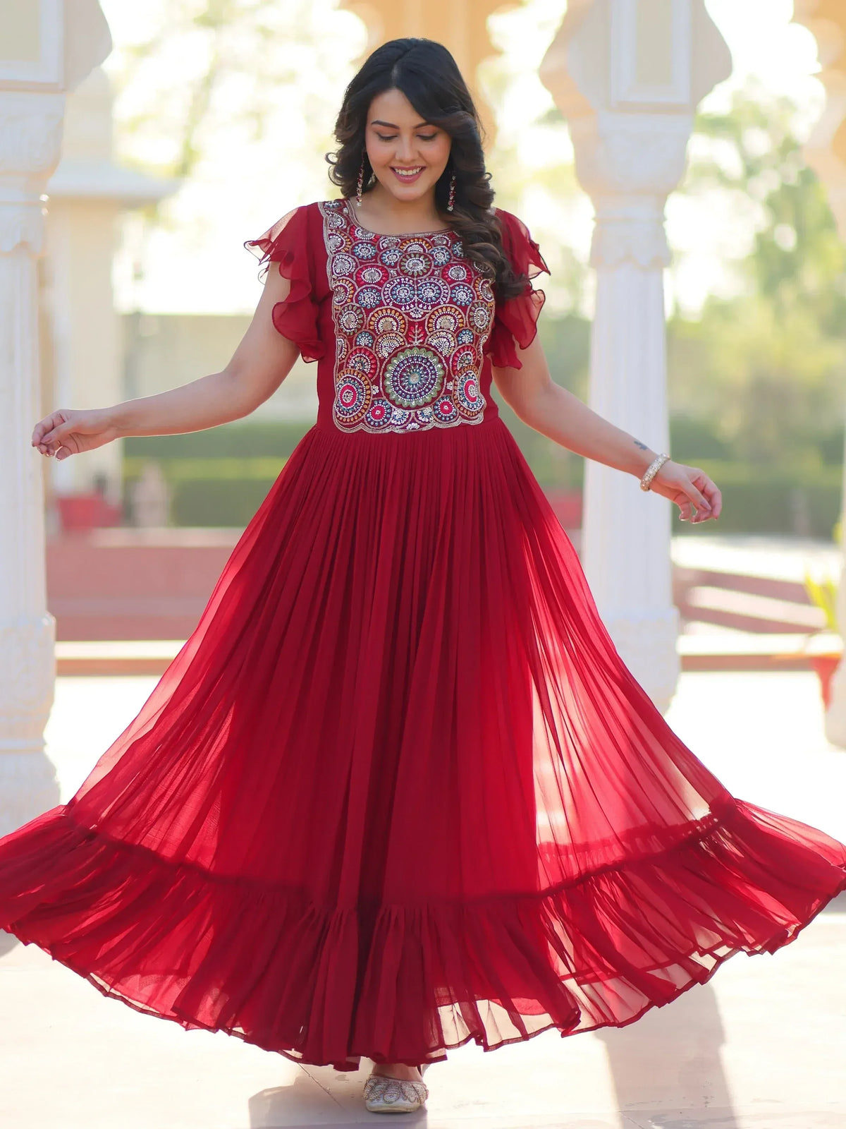 Red ethnic gown with intricate embroidery and flared pleated skirt, perfect for festive occasions.
