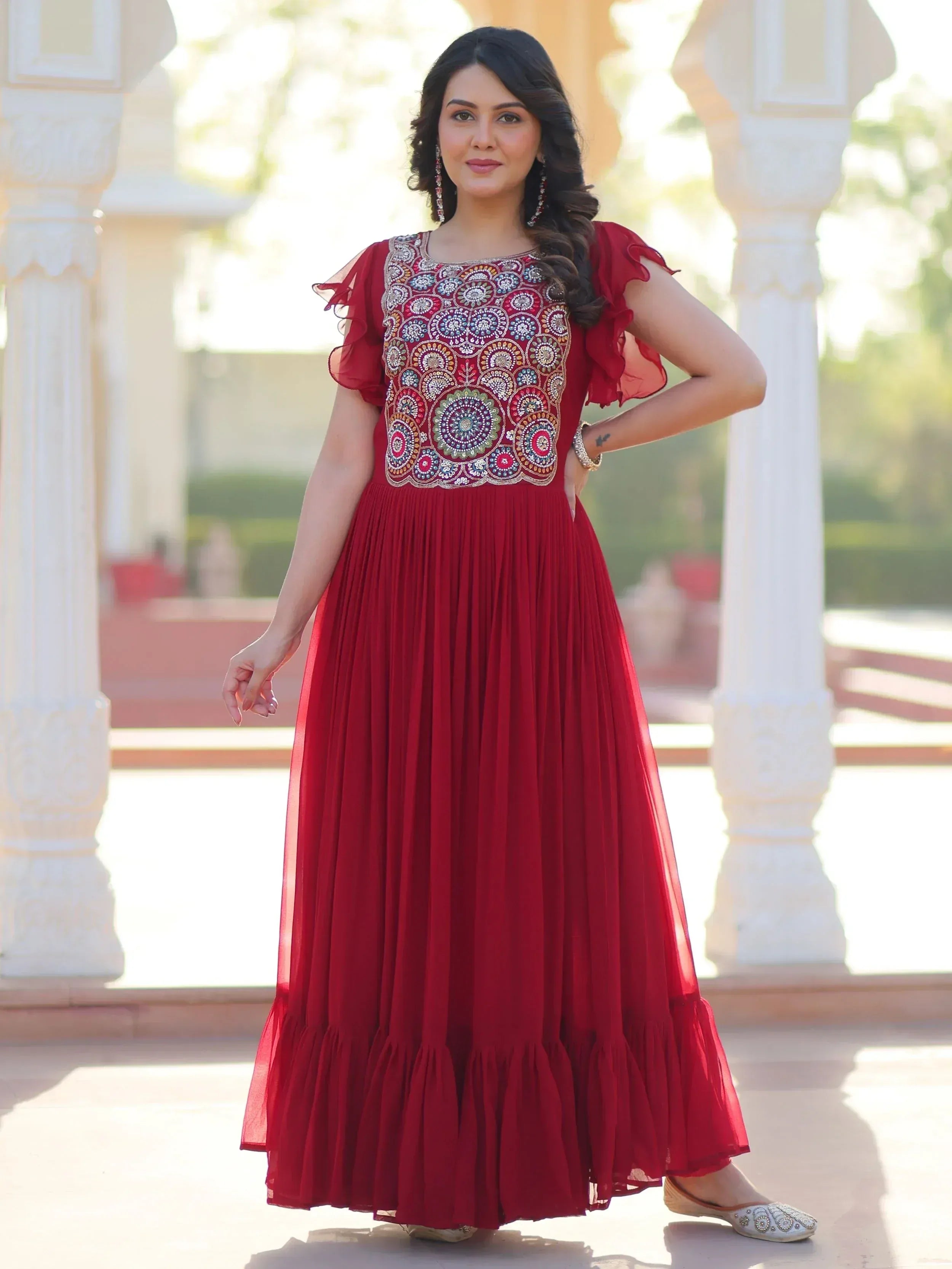 Red ethnic gown with intricate embroidery, ruffled sleeves, and pleated skirt, perfect for Indian occasions.