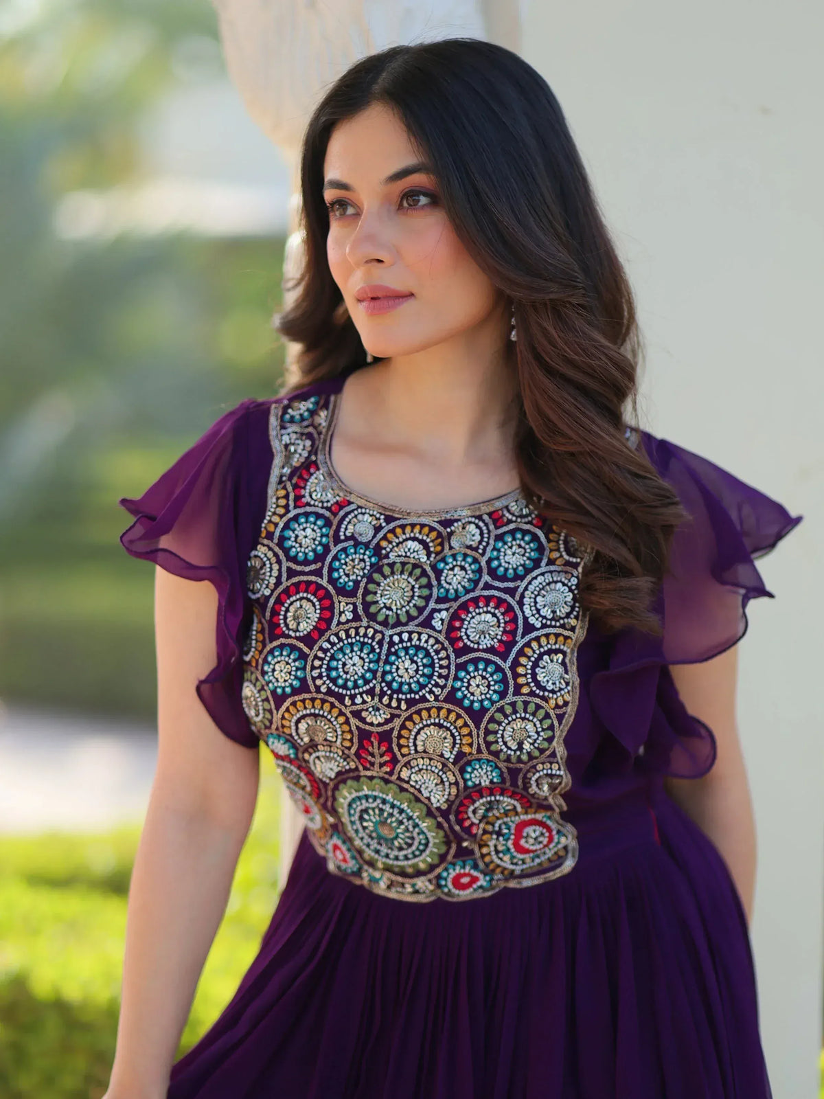 Purple ethnic gown with colorful floral embroidery, ruffled sleeves, and pleated skirt for festive occasions