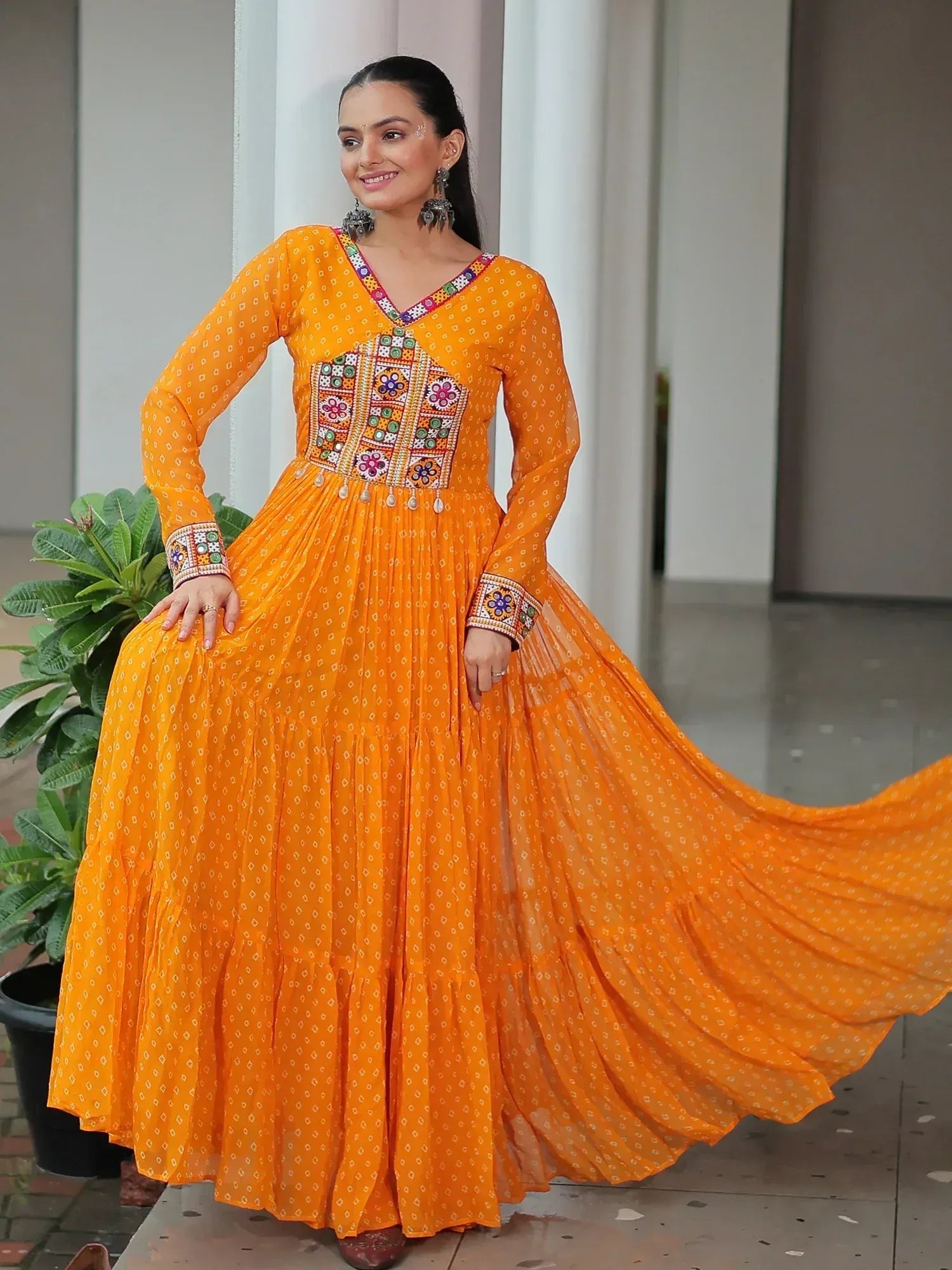 Vibrant orange ethnic gown with colorful mirror work, perfect for Indian festive occasions and celebrations.